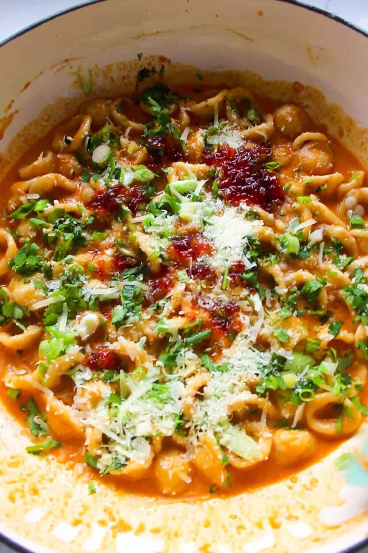 Coriander, spring onions, chilli jam and parmesan on top of gochujang pasta in a large white skillet.
