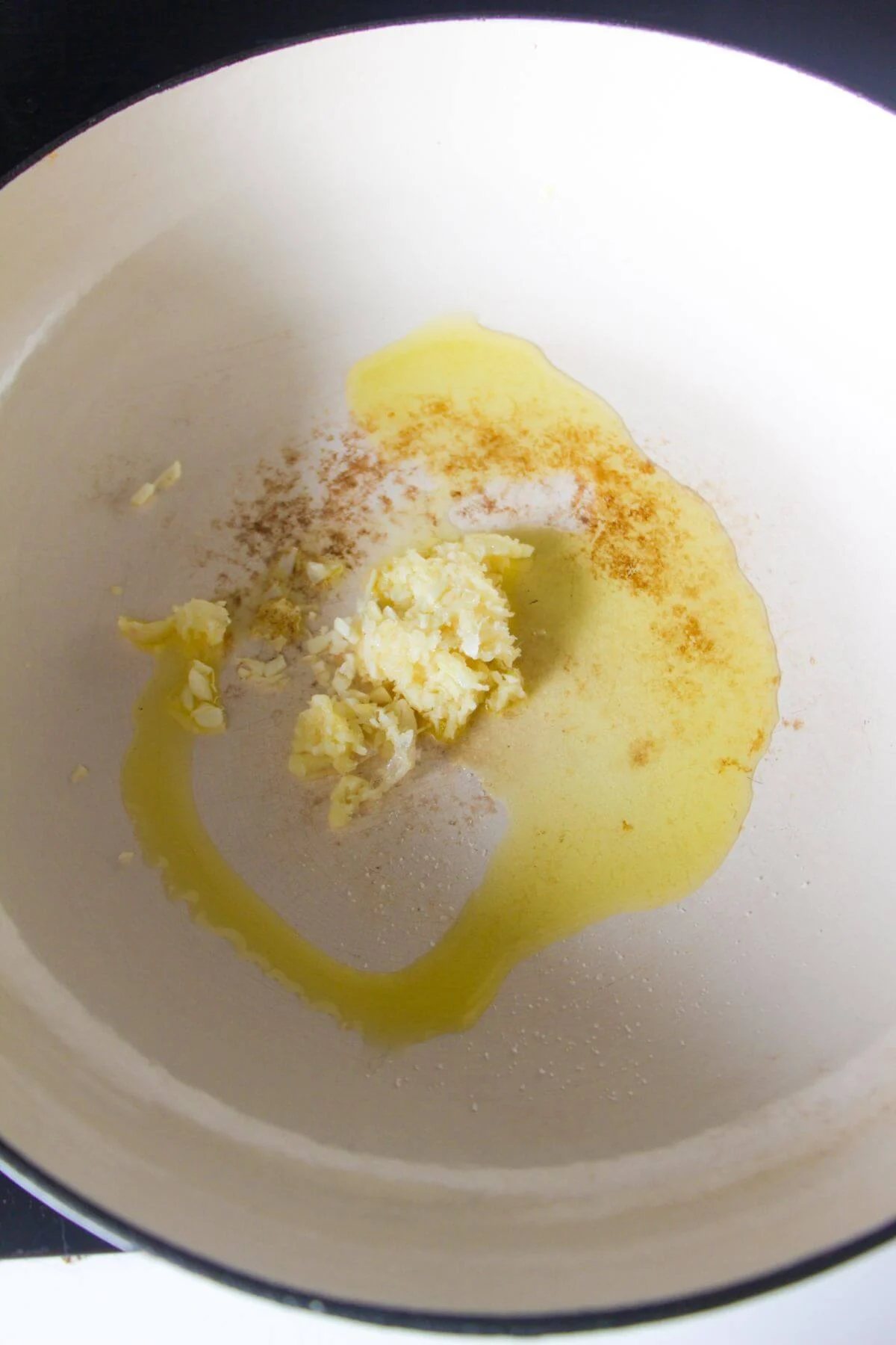 Crushed garlic and olive oil in a large white skillet.