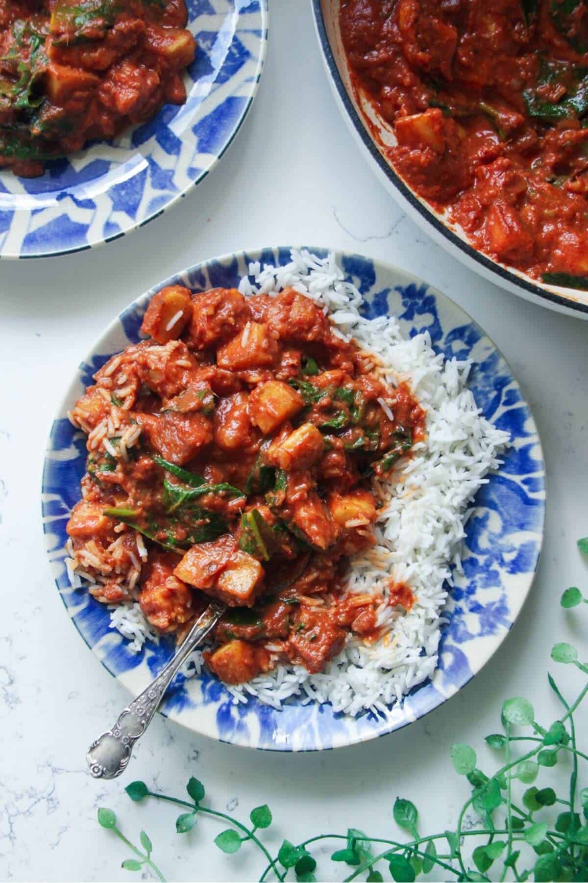 Creamy halloumi curry with spinach on rice on a small plate.