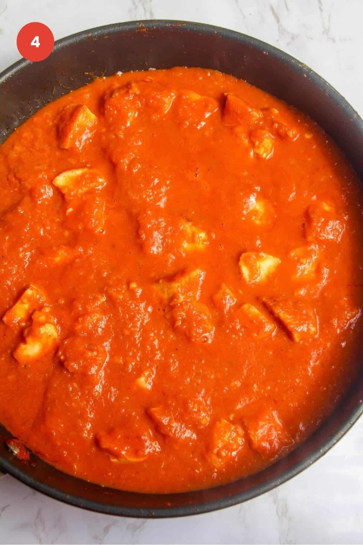 Halloumi added to coconut tomato sauce in a pan.
