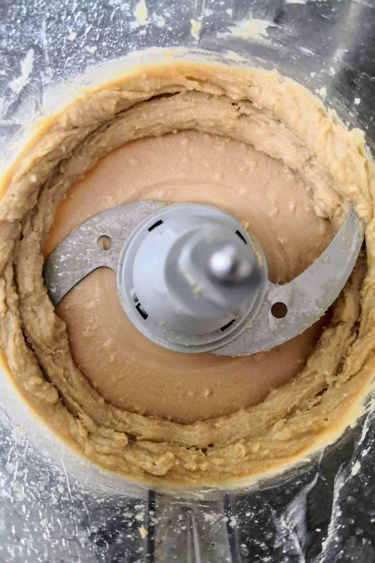 Whipped tahini in the bowl of a food processor from above