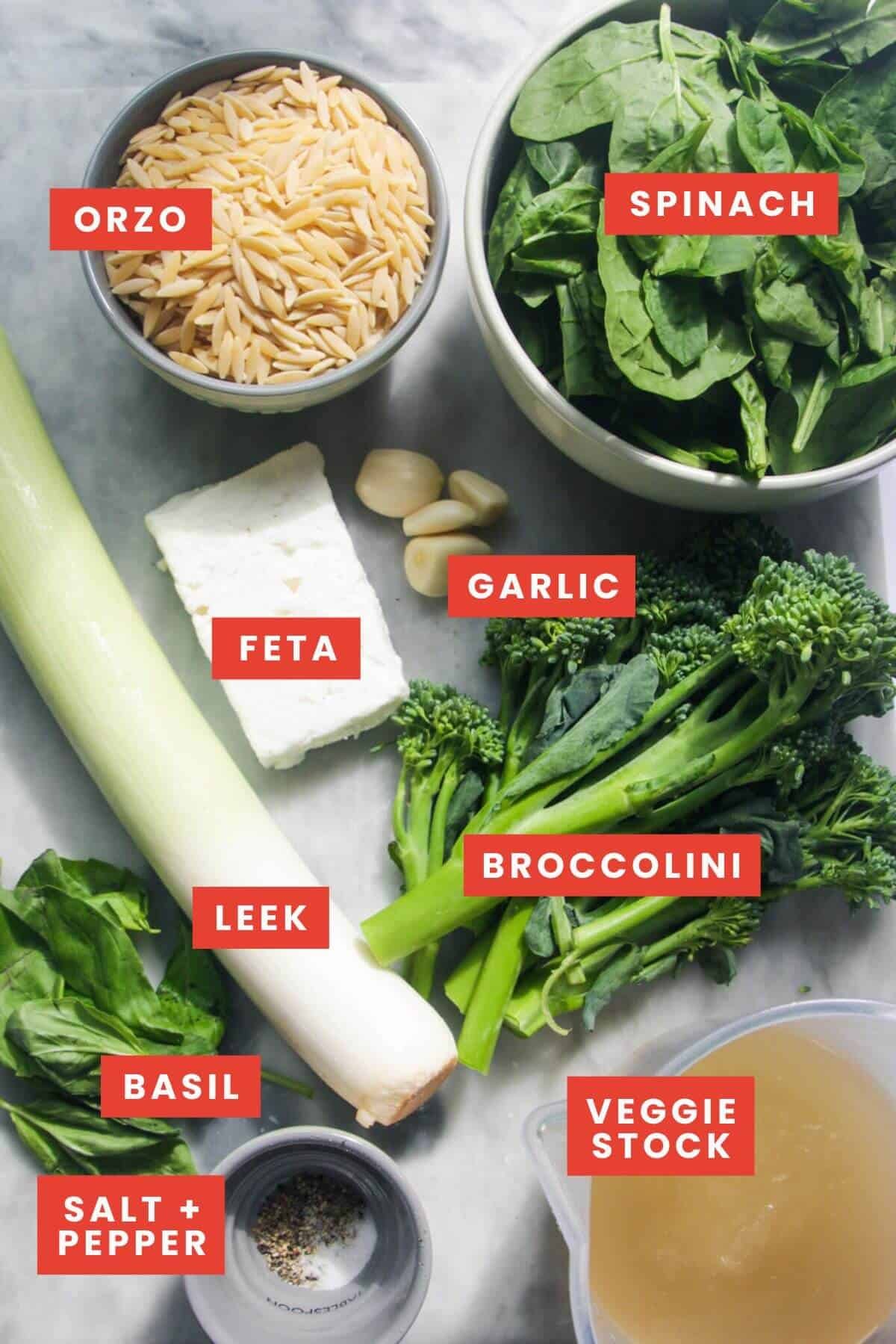 Creamy spinach and feta orzo ingredients on a grey marble background.