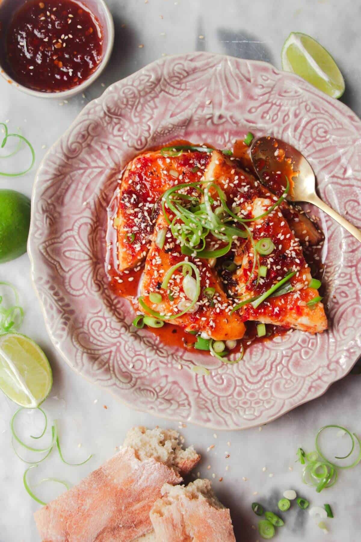 Four wedges of sweet chilli haloumi on a pink plate with more sweet chilli on the side.