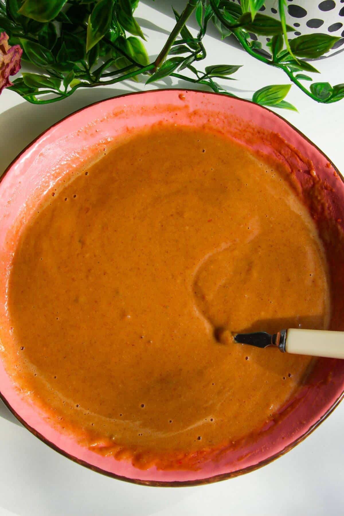 Peanut satay sauce mixed in a pink bowl.
