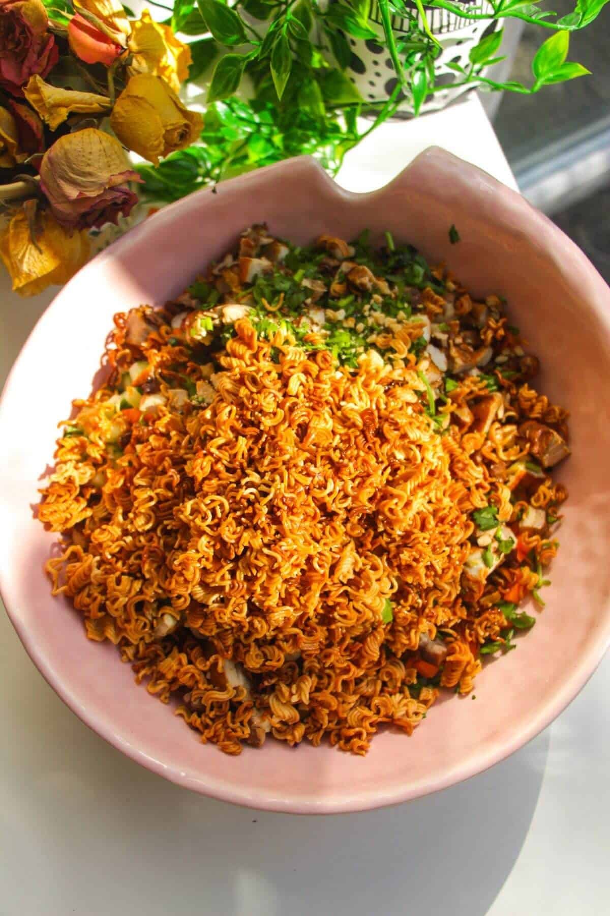 Ingredients for crispy ramen salad in a pink bowl.