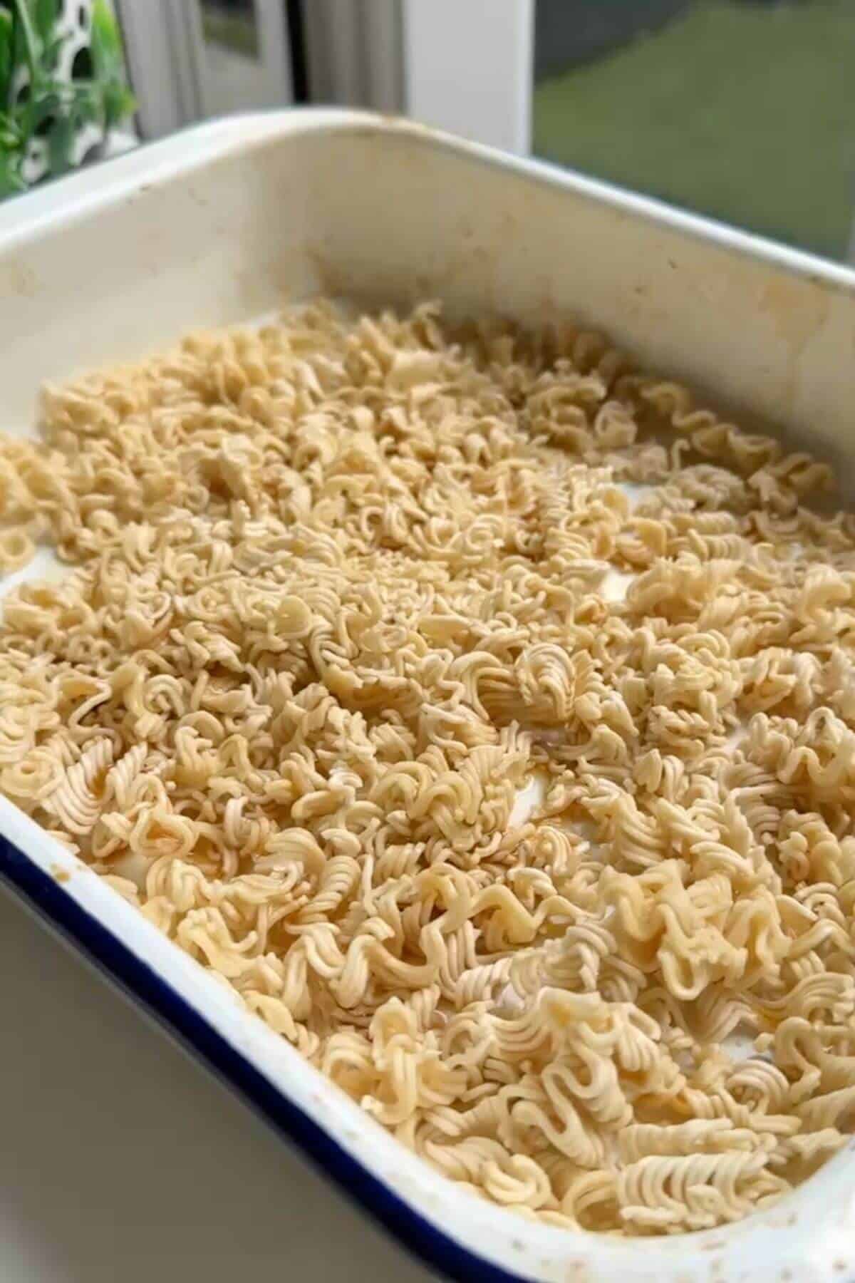 Ramen noodle cakes broken into pieces in an oven tray.
