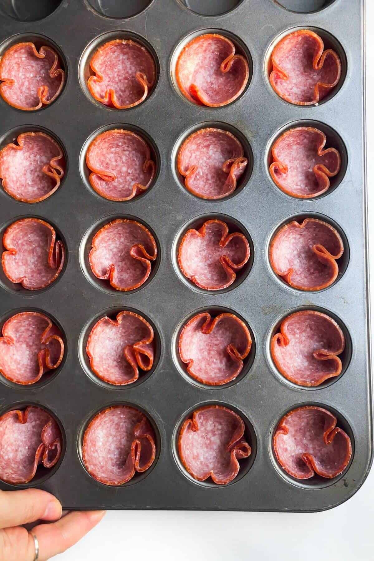 Salami slices in a mini muffin tin.