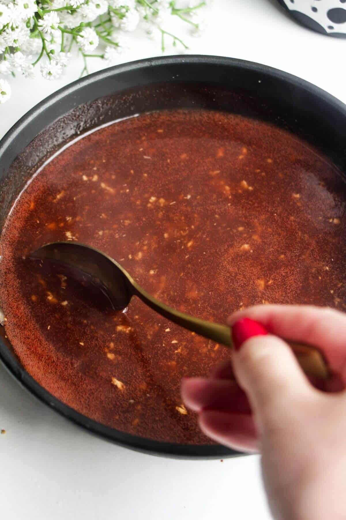 Spoon sitrring sweet and sour sauce in a small pan.
