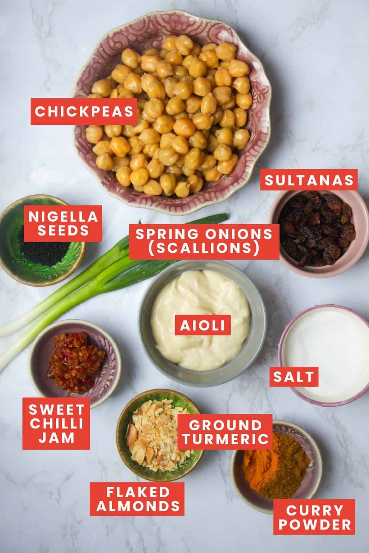 Ingredients for coronation chickpeas, laid out on a white marble background and labelled.