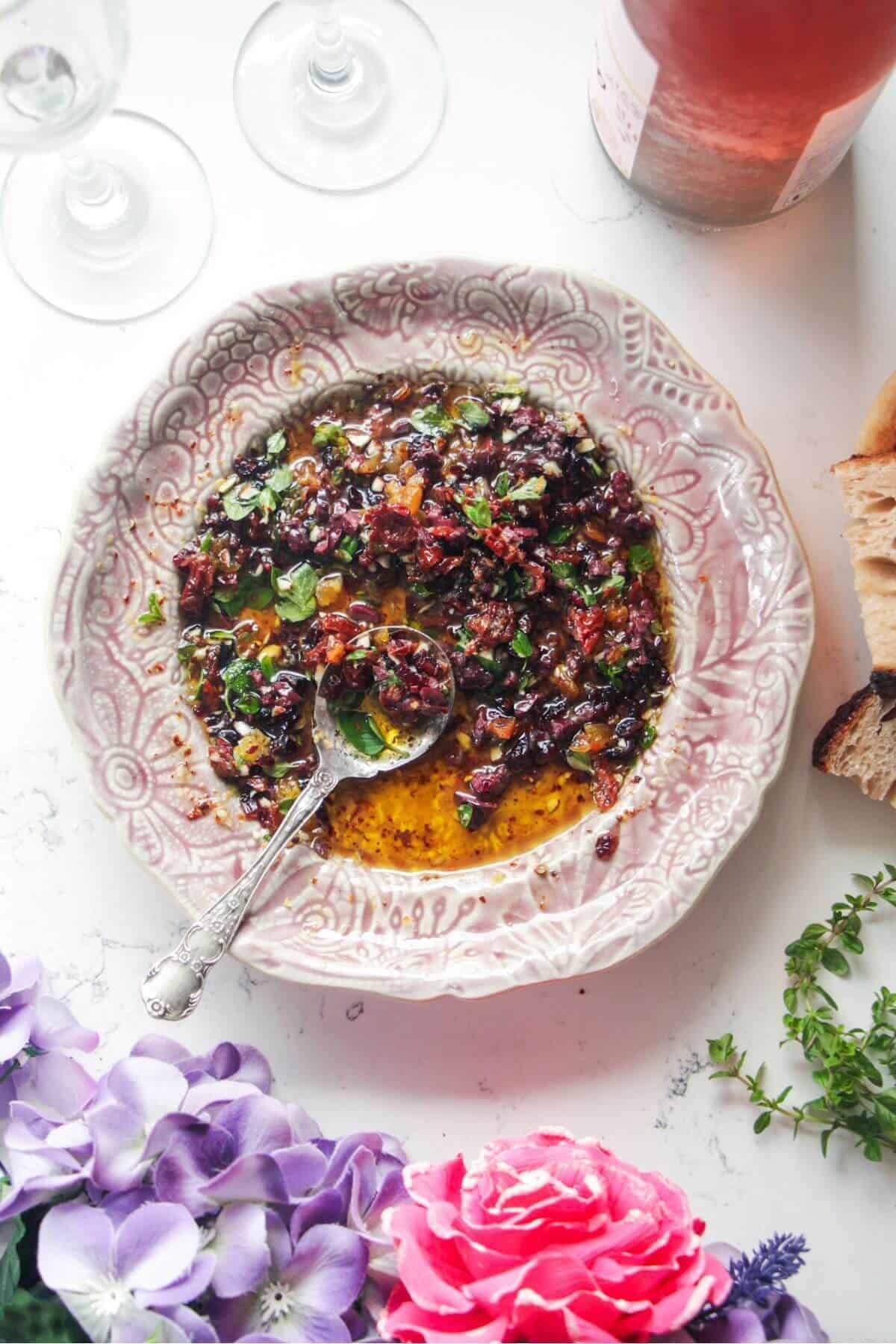 Date night bread dipping oil on a pink plate with a silver spoon.