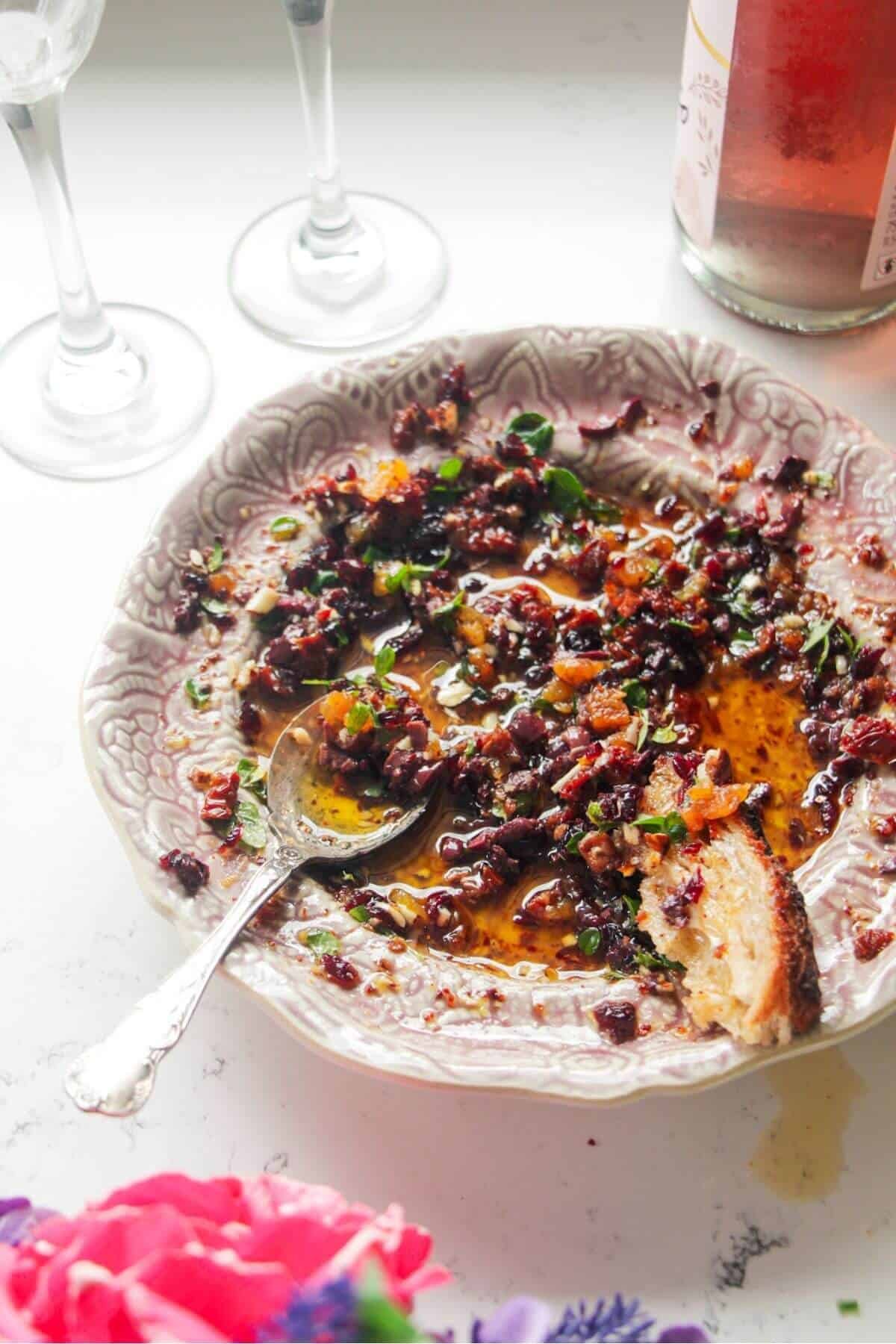 Date night bread dipping oil on a pink plate with a silver spoon.
