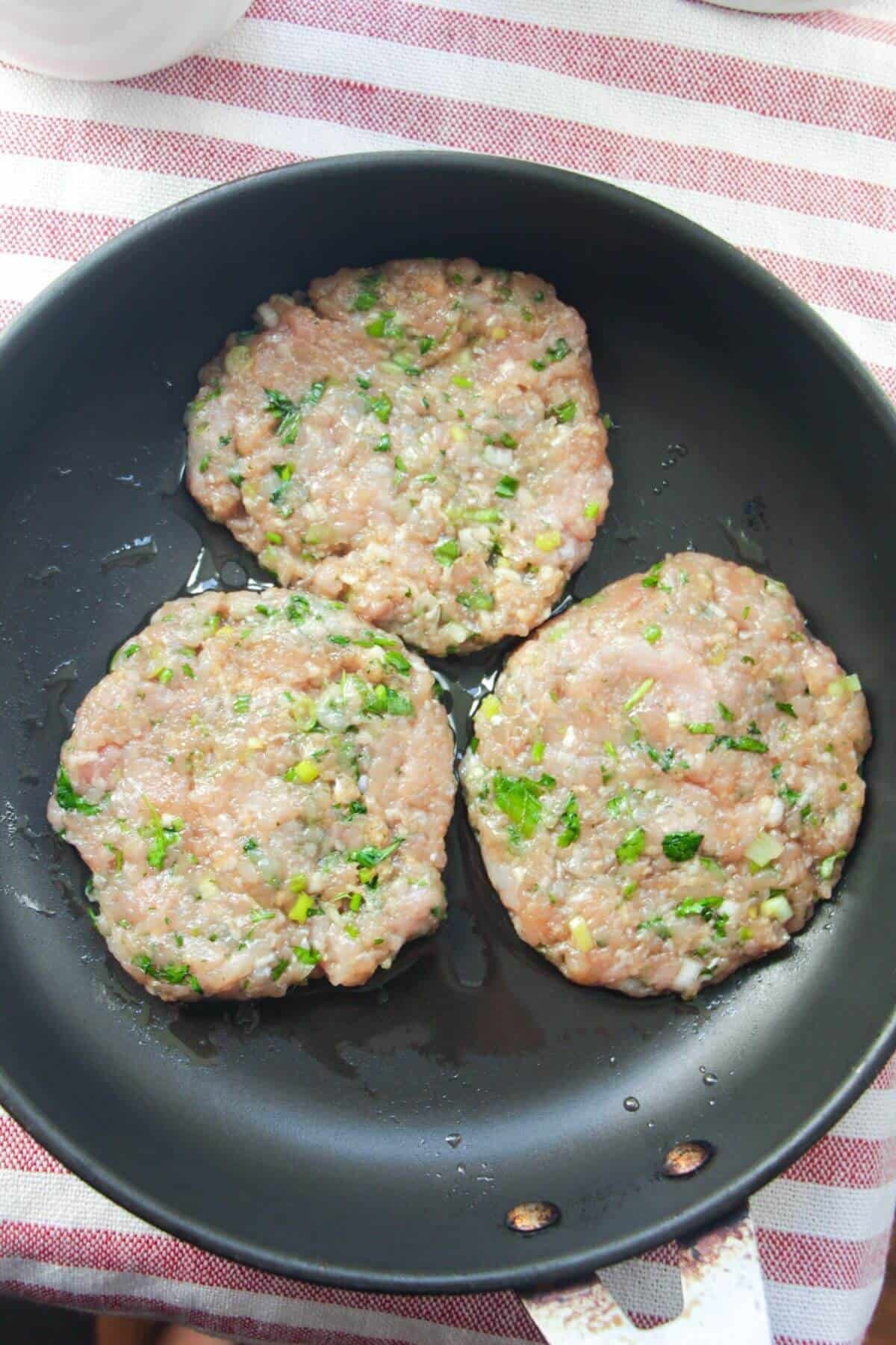 Three dumpling patties in a small pan.