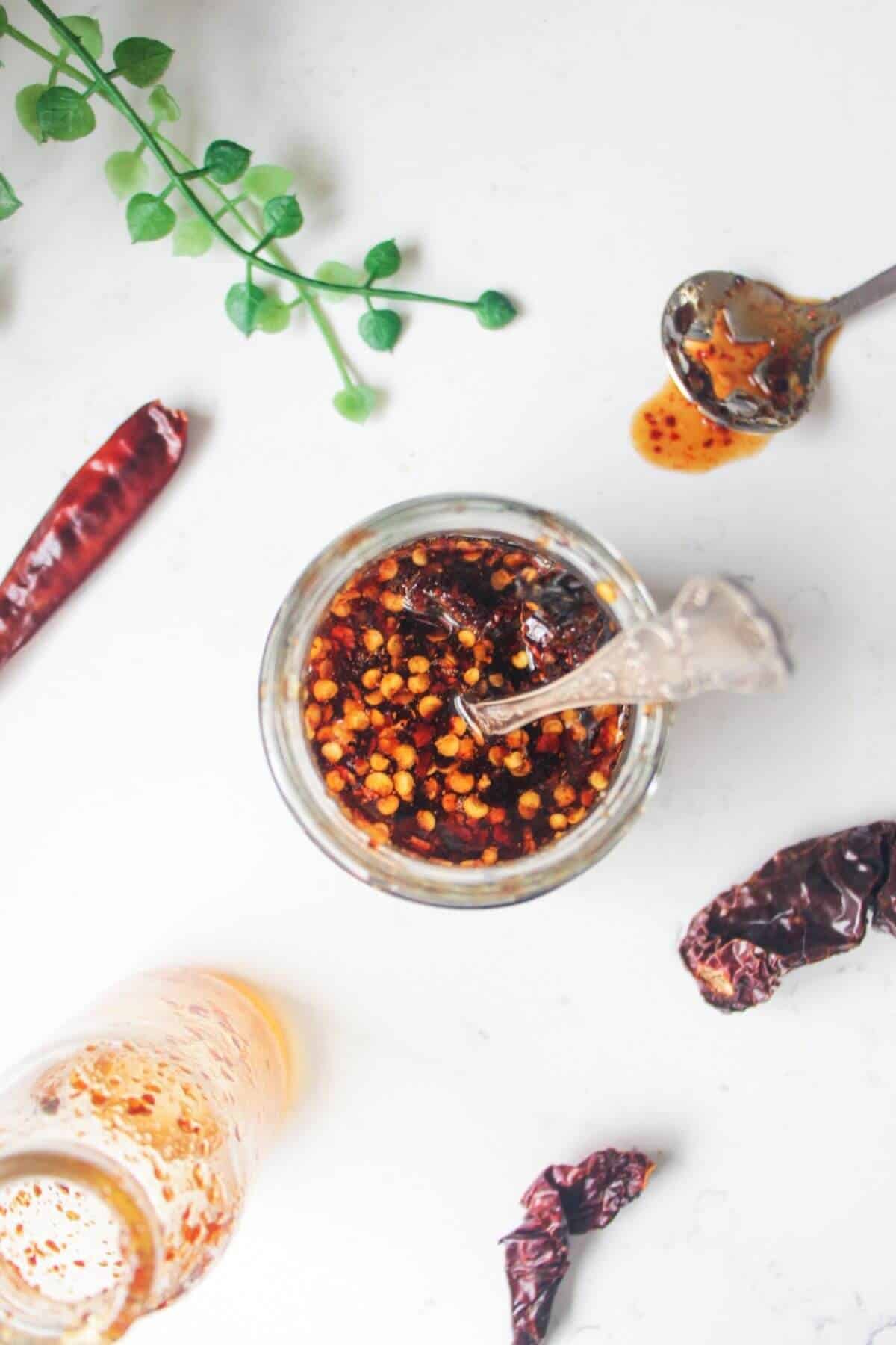 Hot honey sauce in a glass jar with silver spoon inside.