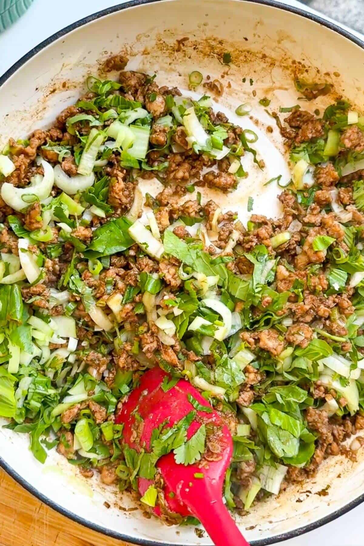 Bok choi added and tossed through ground chicken.