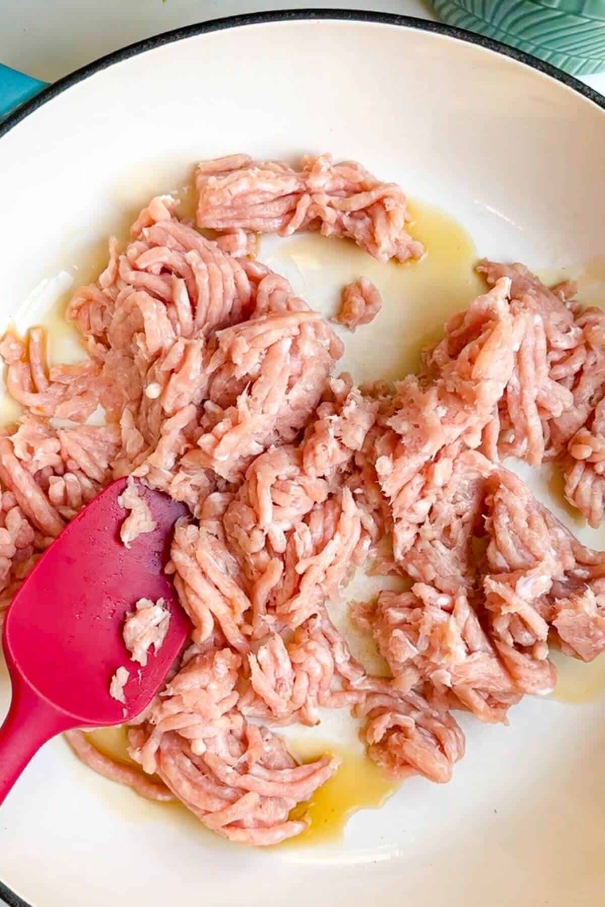 Ground chicken in a large pan.