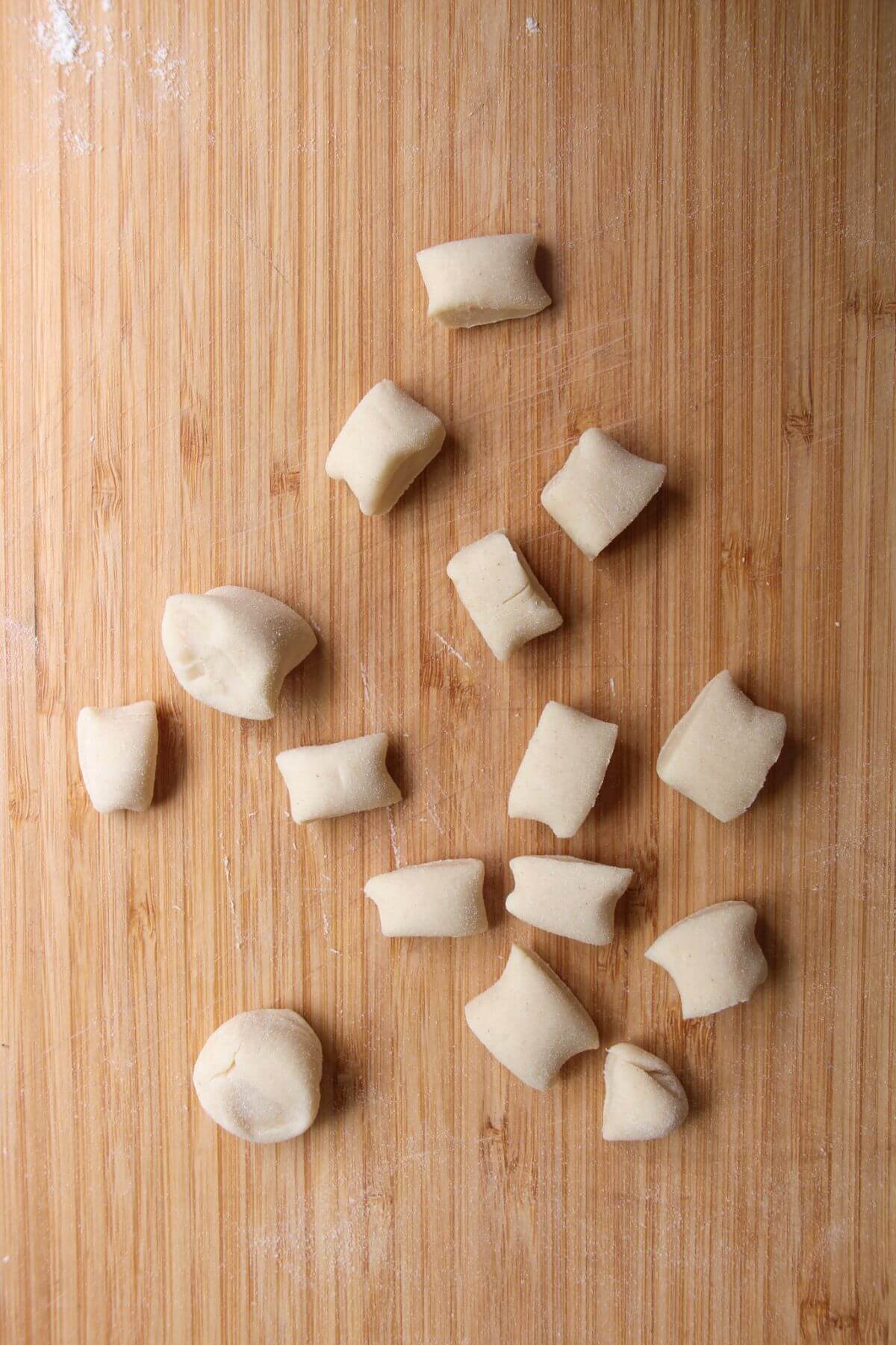 Small pieces of dough laid out on a large wooden board.