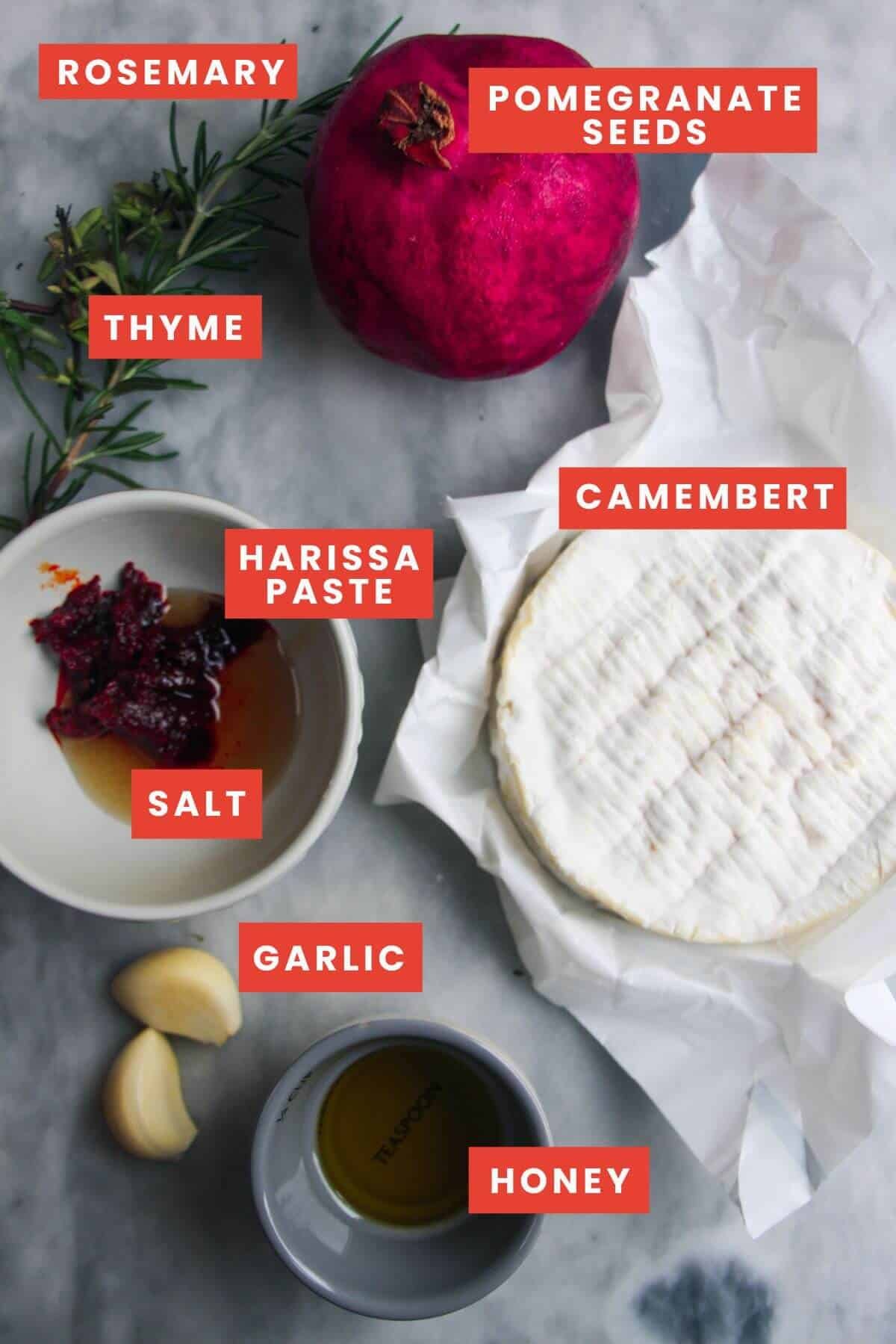 Ingredients for baked camembert laid out on a grey marble background and labelled.
