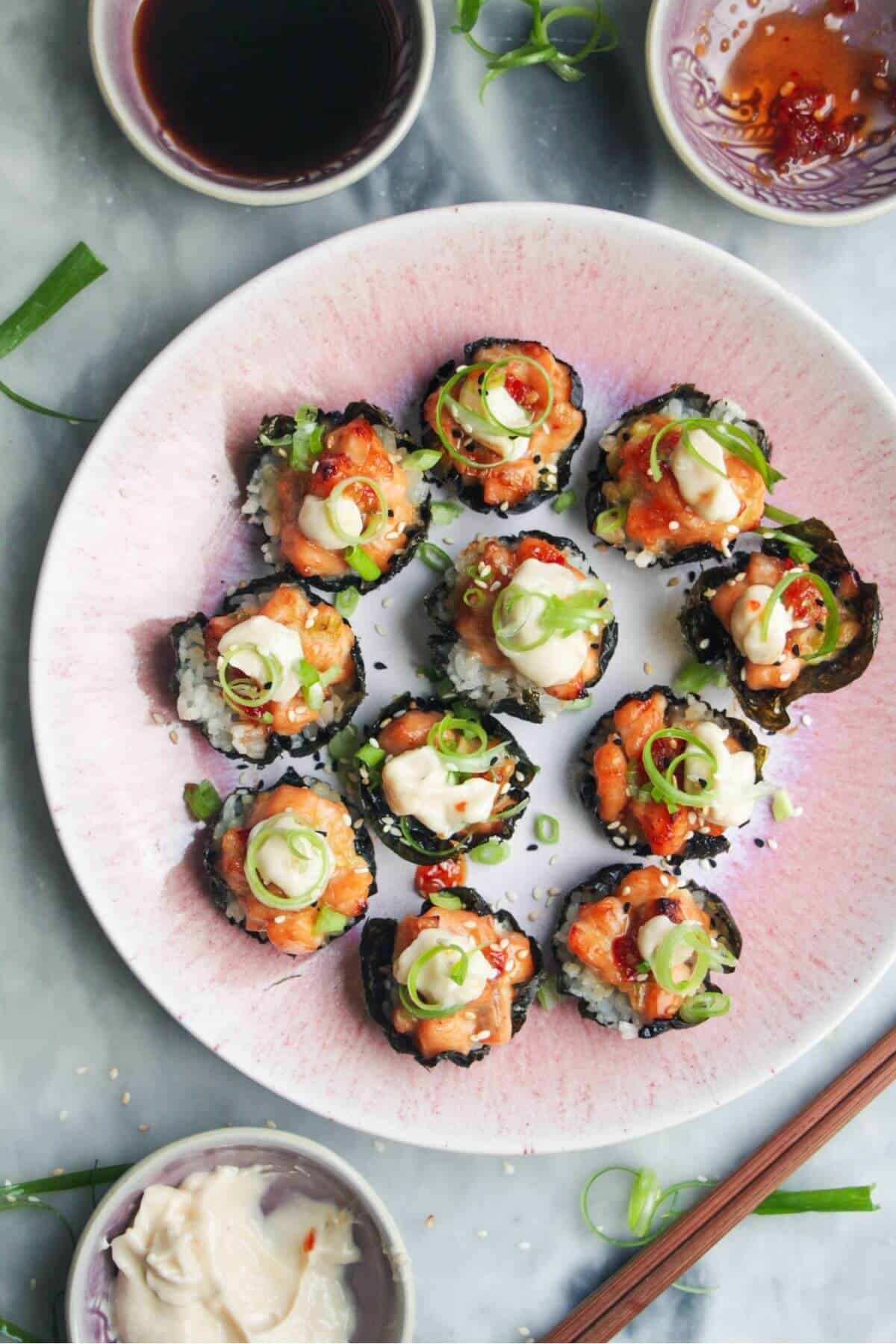 Salmon sushi cups on a pink plate, with aioli and sweet chilli on the side.