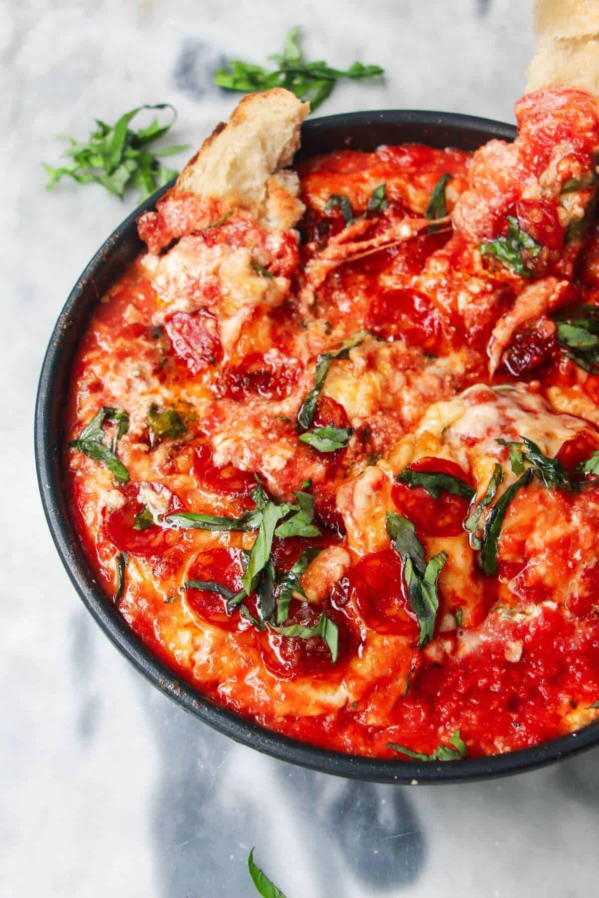 Cheesy pepperoni topped pizza dip with two pieces of bread inside.
