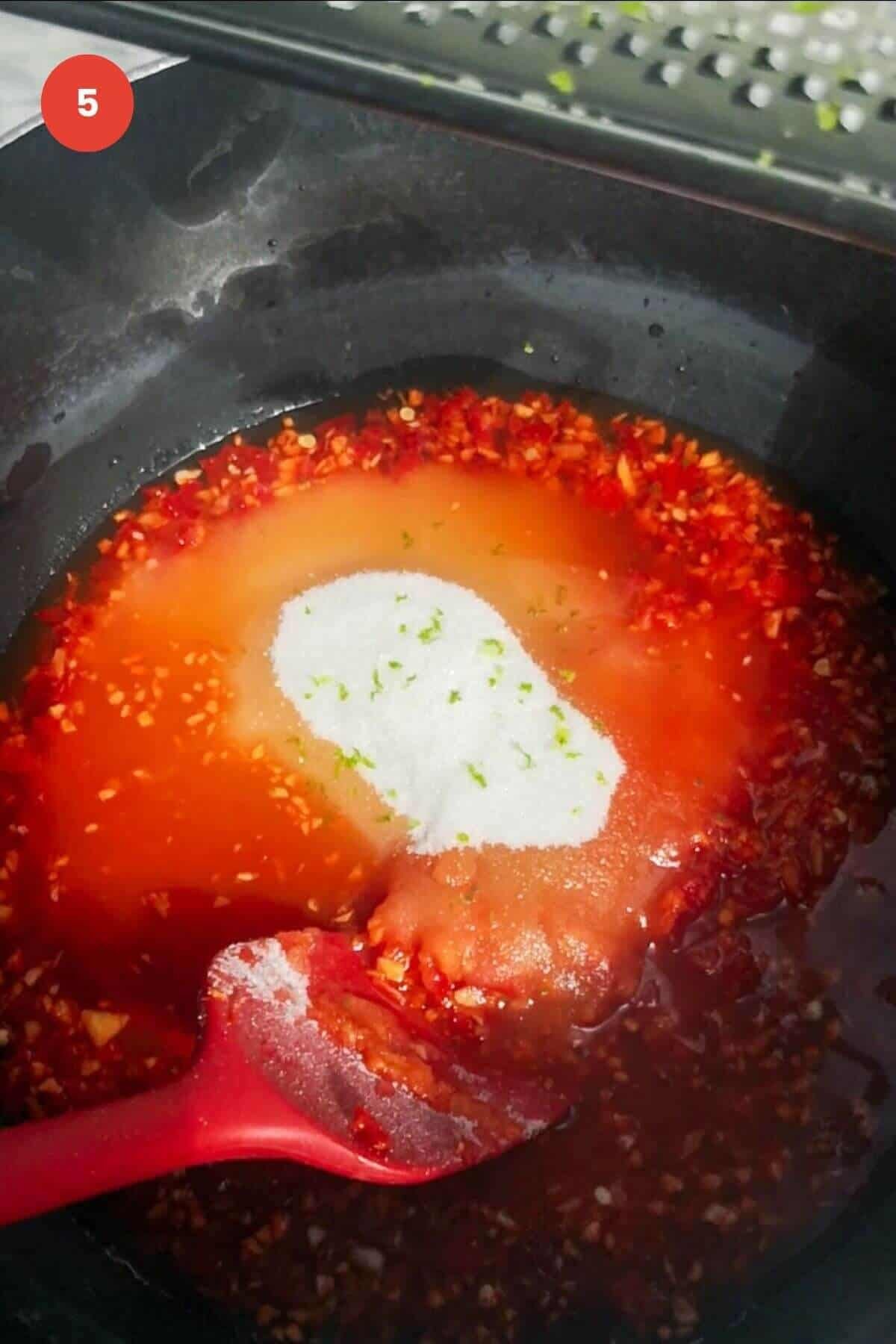 Chili jam ingredients in a pot with sugar and lime zest.