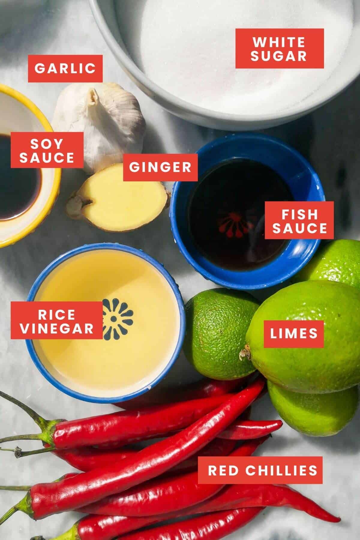 Ingredients for easy chilli jam laid out on a grey marble background, lablled.