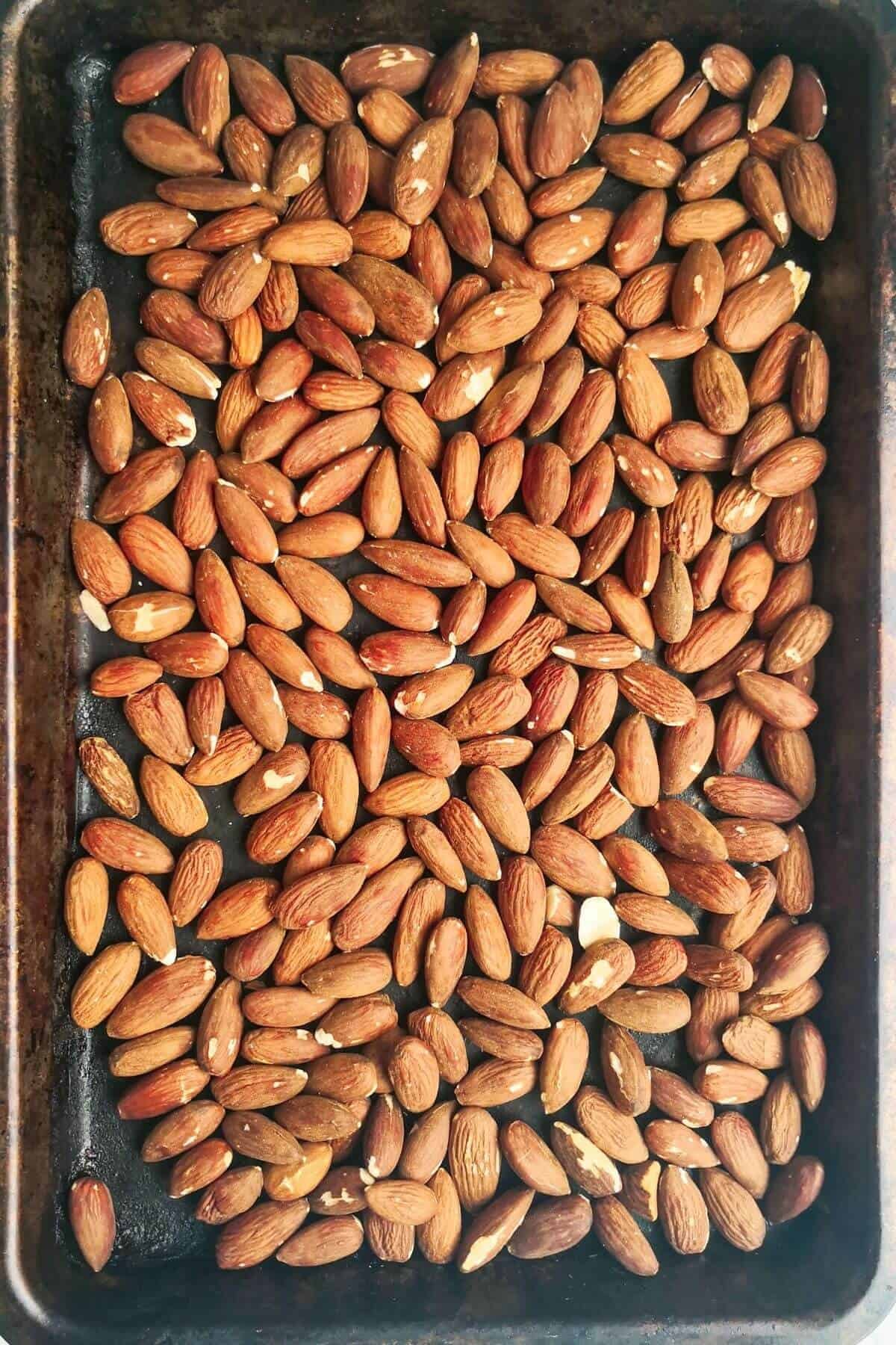Roasted almonds laid out on an oven tray.