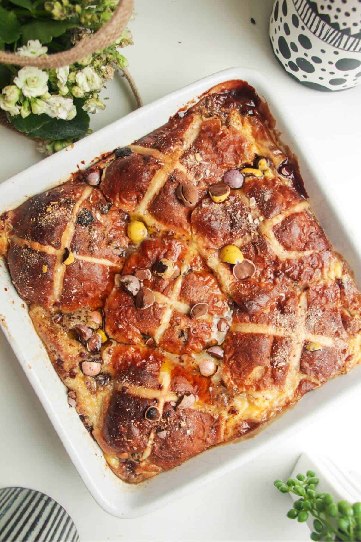 Baked hot cross bun bread and butter pudding in a white baking dish.