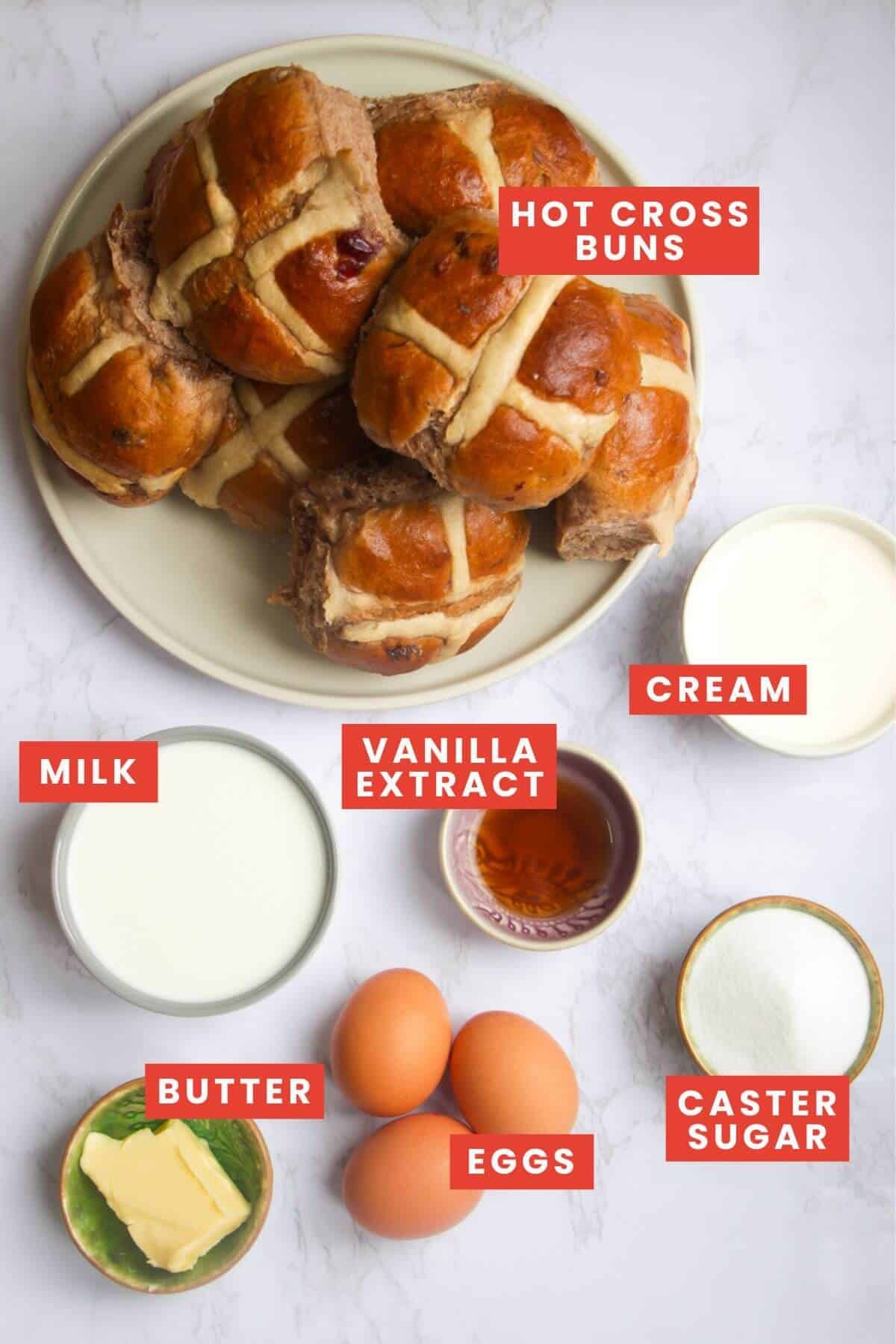 Ingredients for bread and butter pudding laid out on a white marble background and labelled.