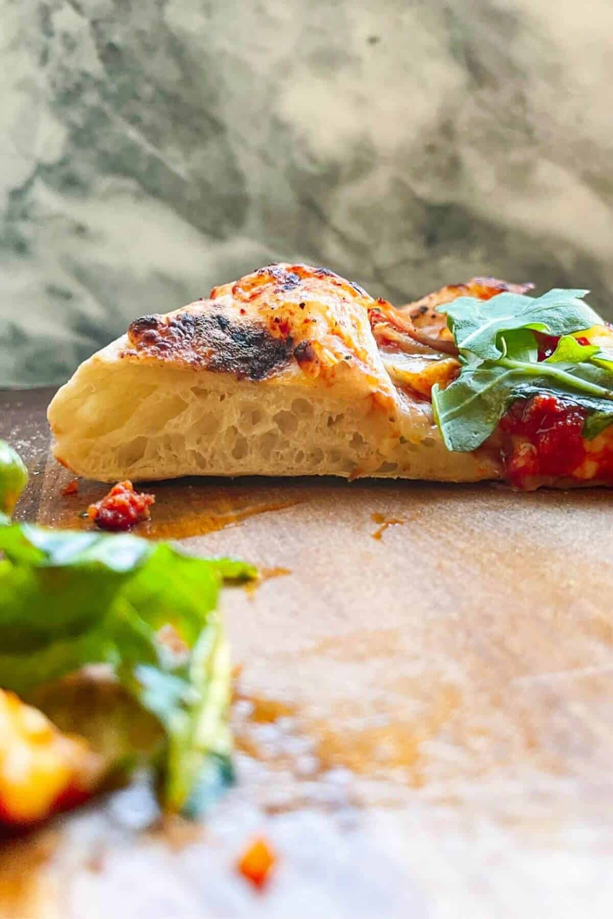 View of cross section of cut pizza crust, showing the air bubbles.