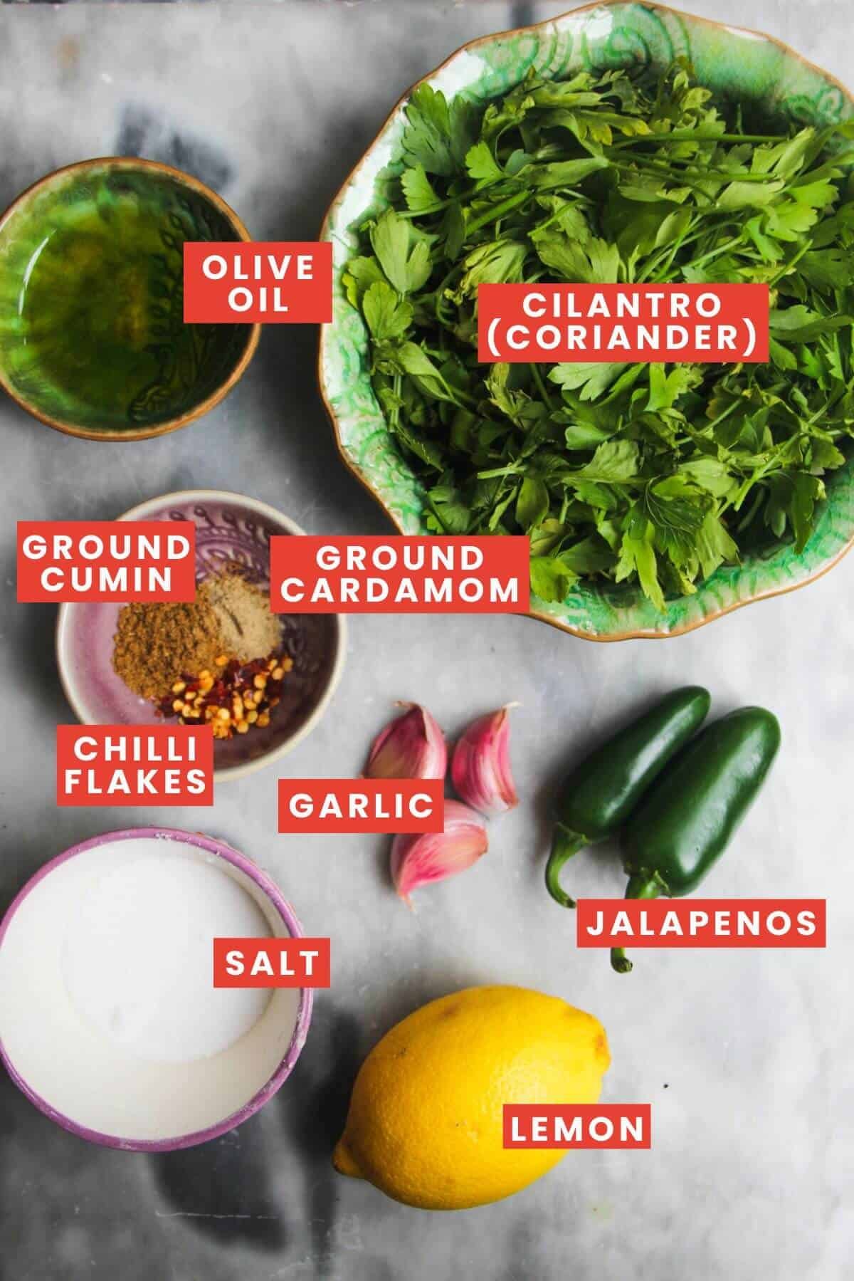Ingredients for zhough sauce laid out on a grey marble background and labelled.
