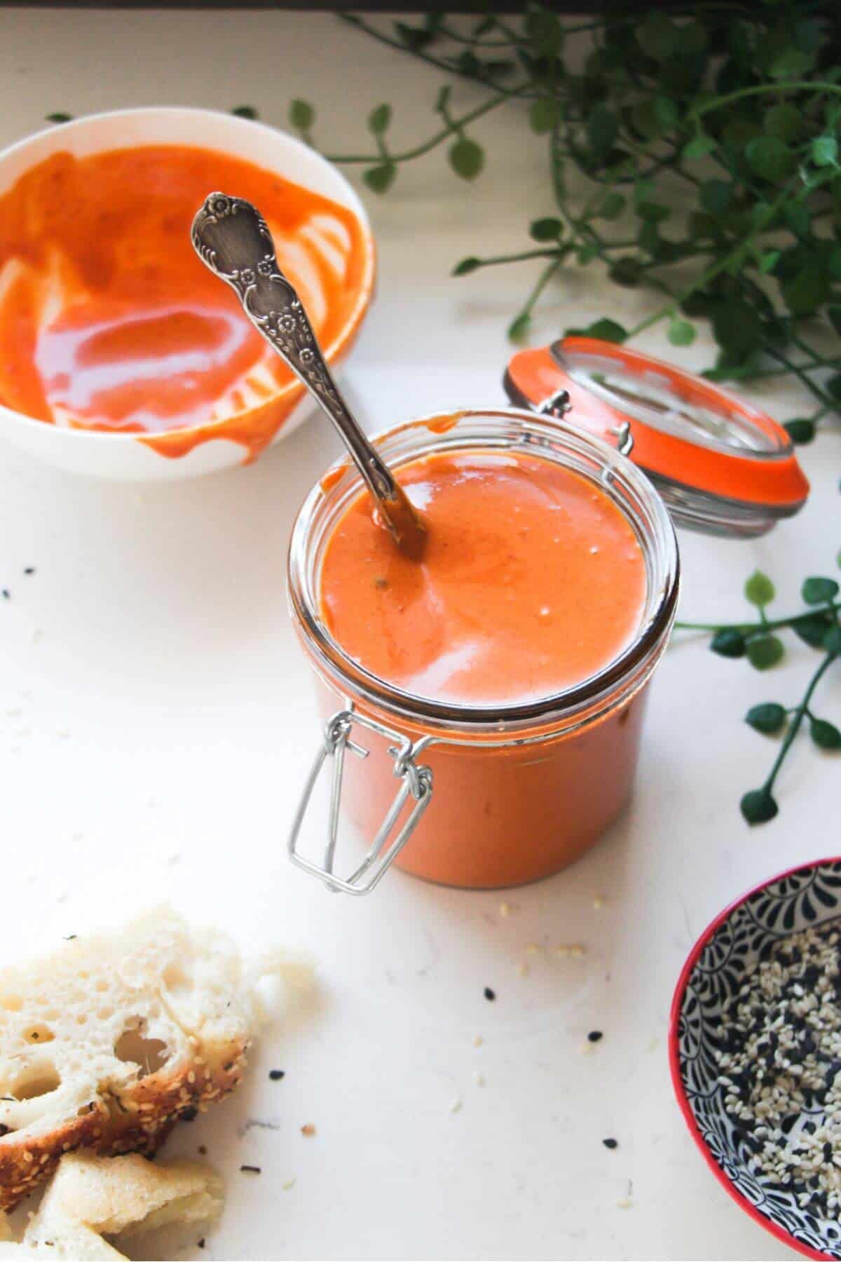 Gochujang mayo in a small glass bowl with a gold spoon, on a grey marble background.