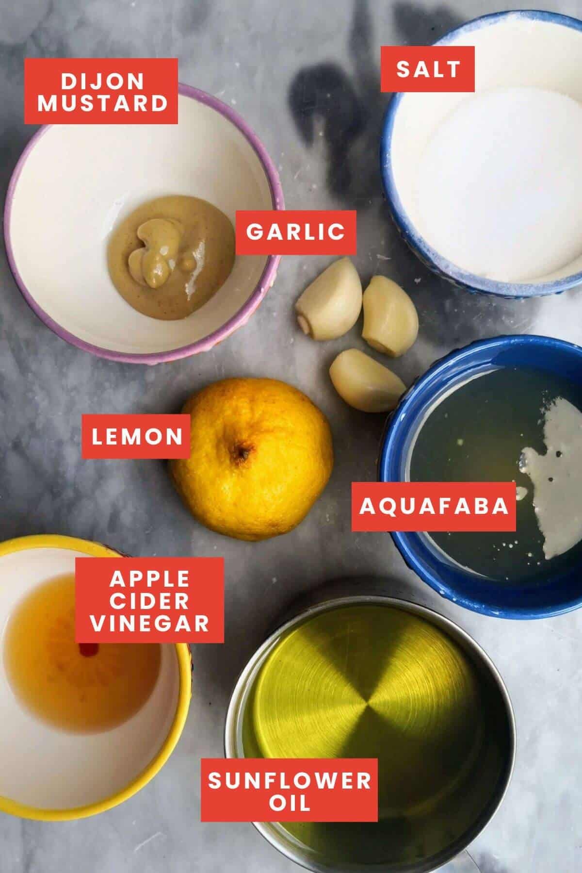 Vegan aioli ingredients laid out on a grey marble surface, labelled.