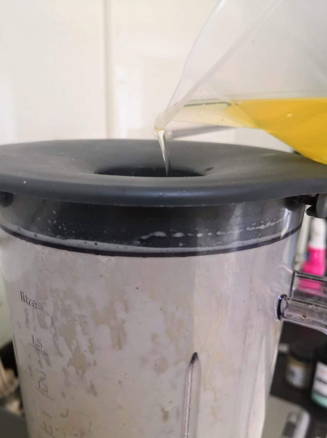 Oiled being poured into the top of a blender.