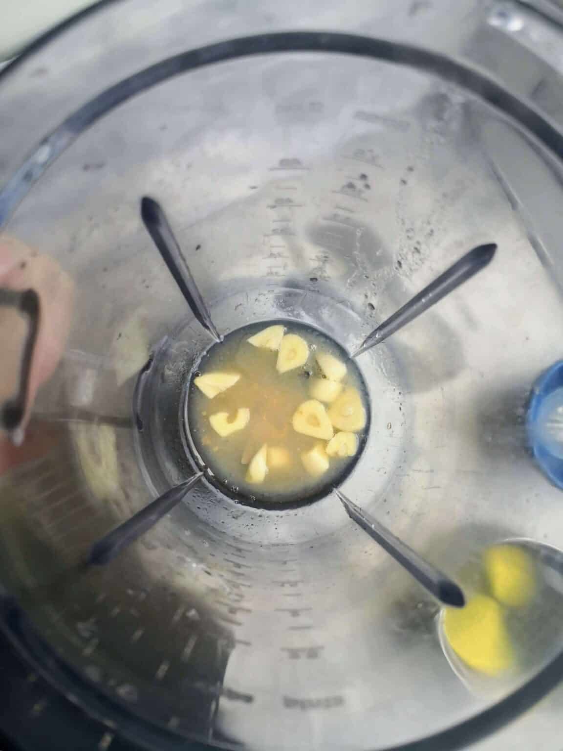 Aquafaba, garlic, lemon juice and salt in a clear blender looking down from above