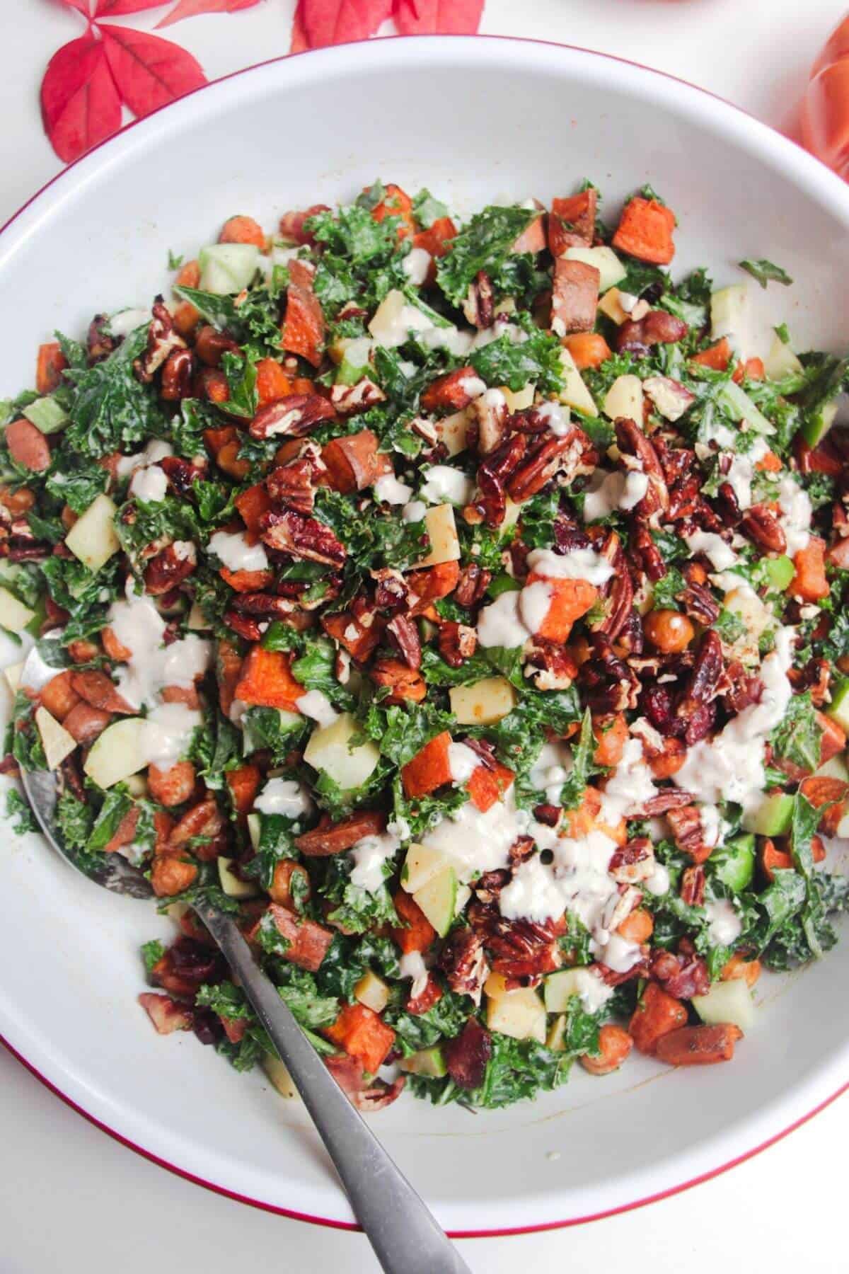 Tahini dressing drizzle on top of sweet potato kale salad in a bowl.