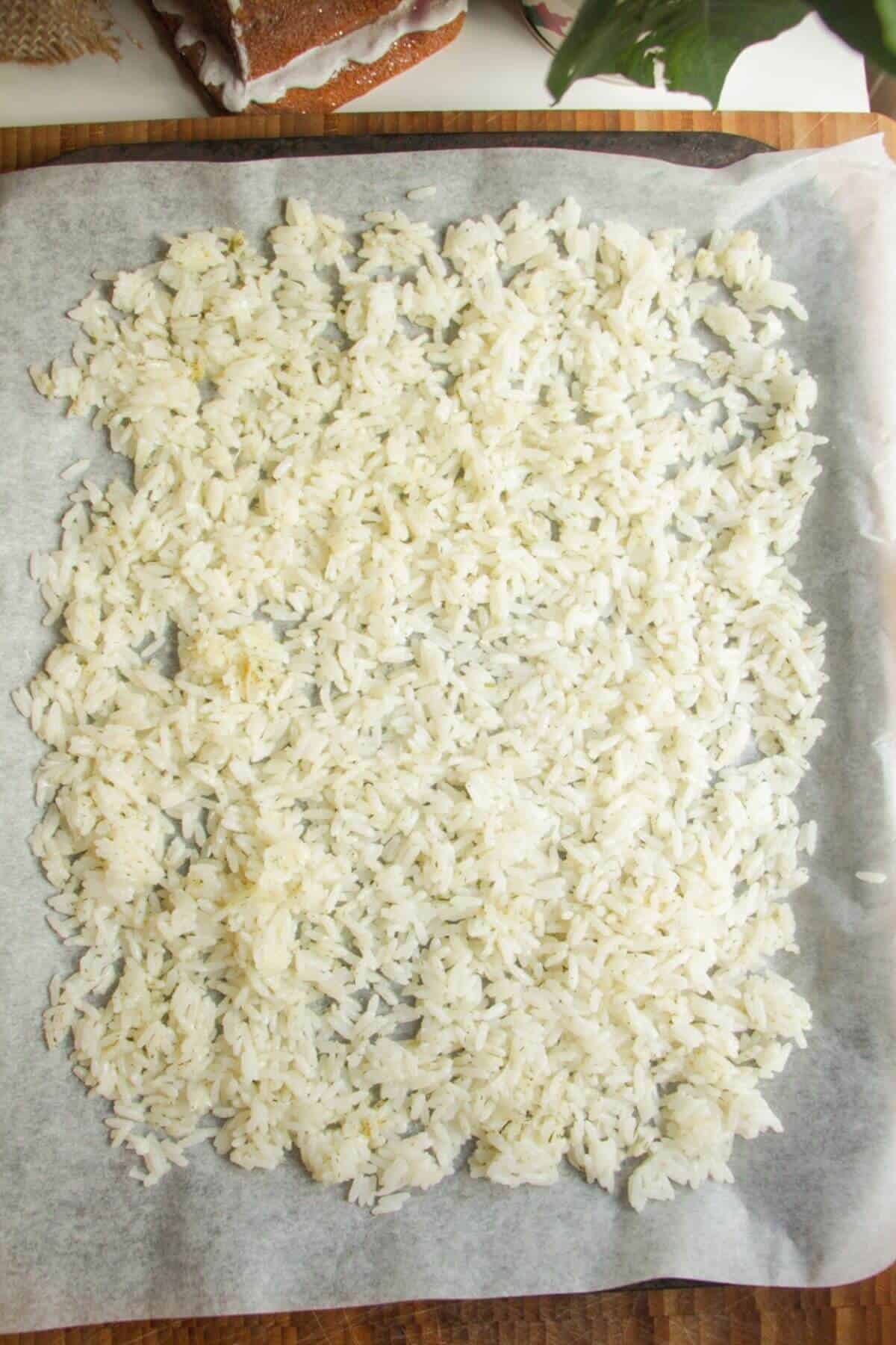 Rice spread out on a lined oven tray.