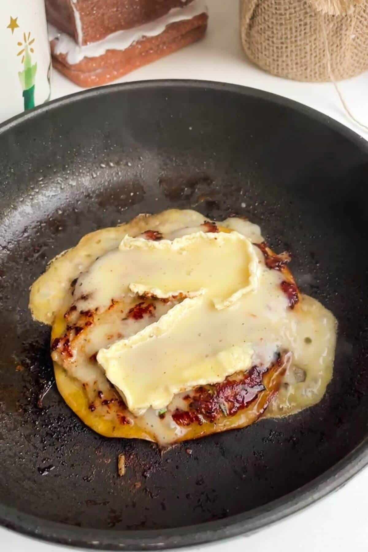Two slices of brie melted on top of smash taco in a small pan