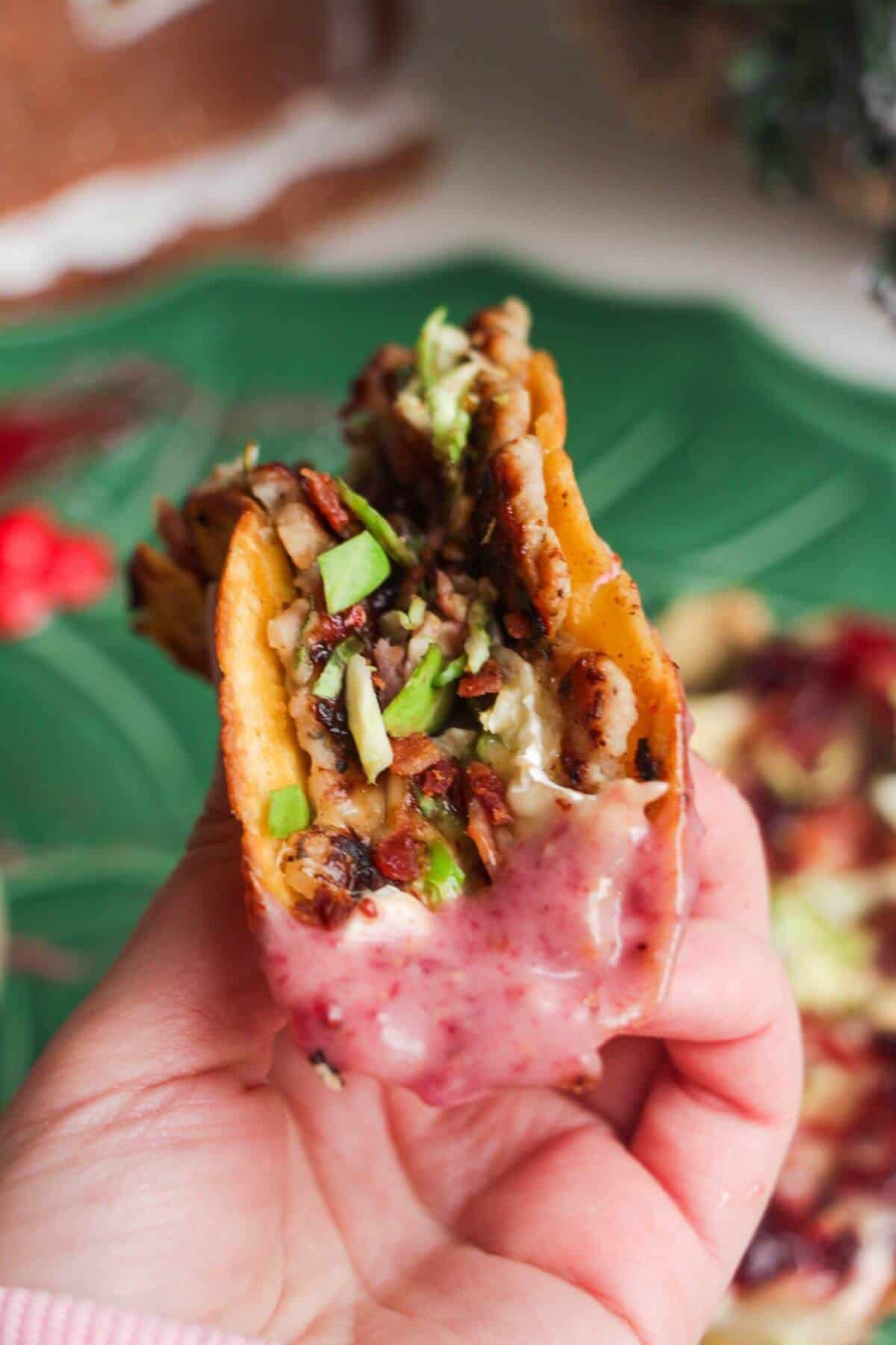 Holding up festive smash taco dipped in cranberry aioli.