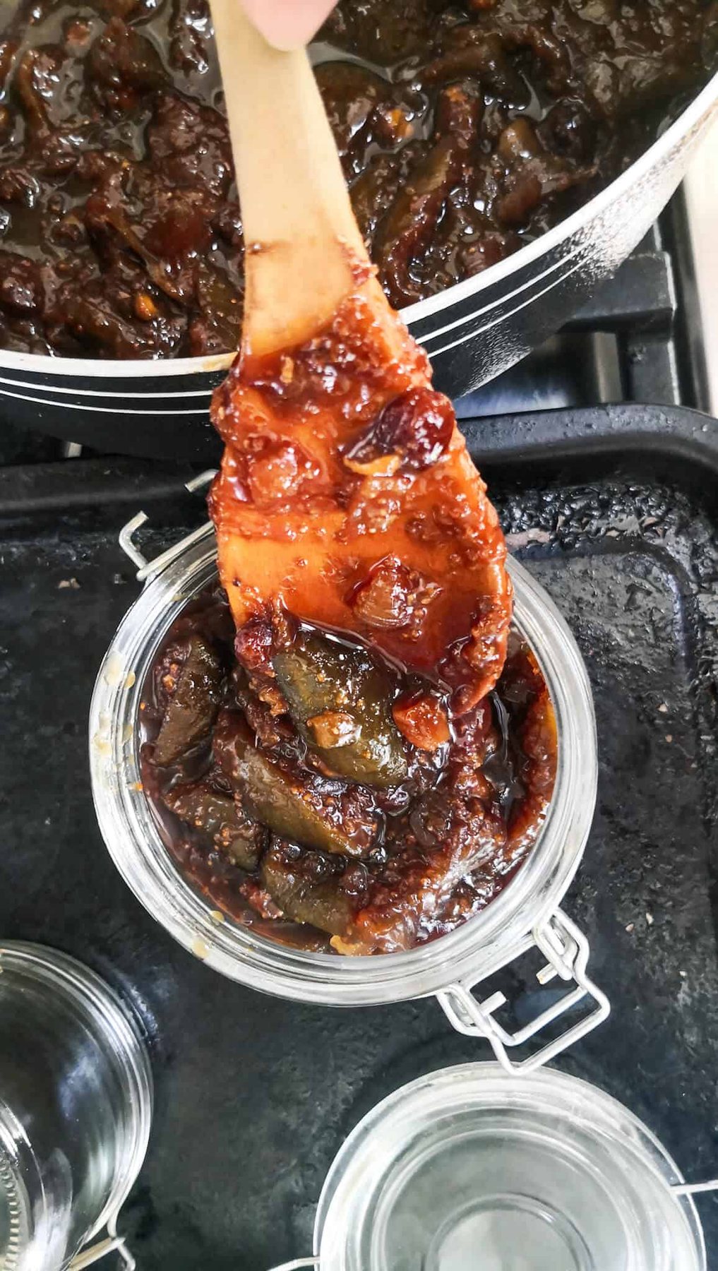 Large wooden spoon transferring chutney into sterilised jars.