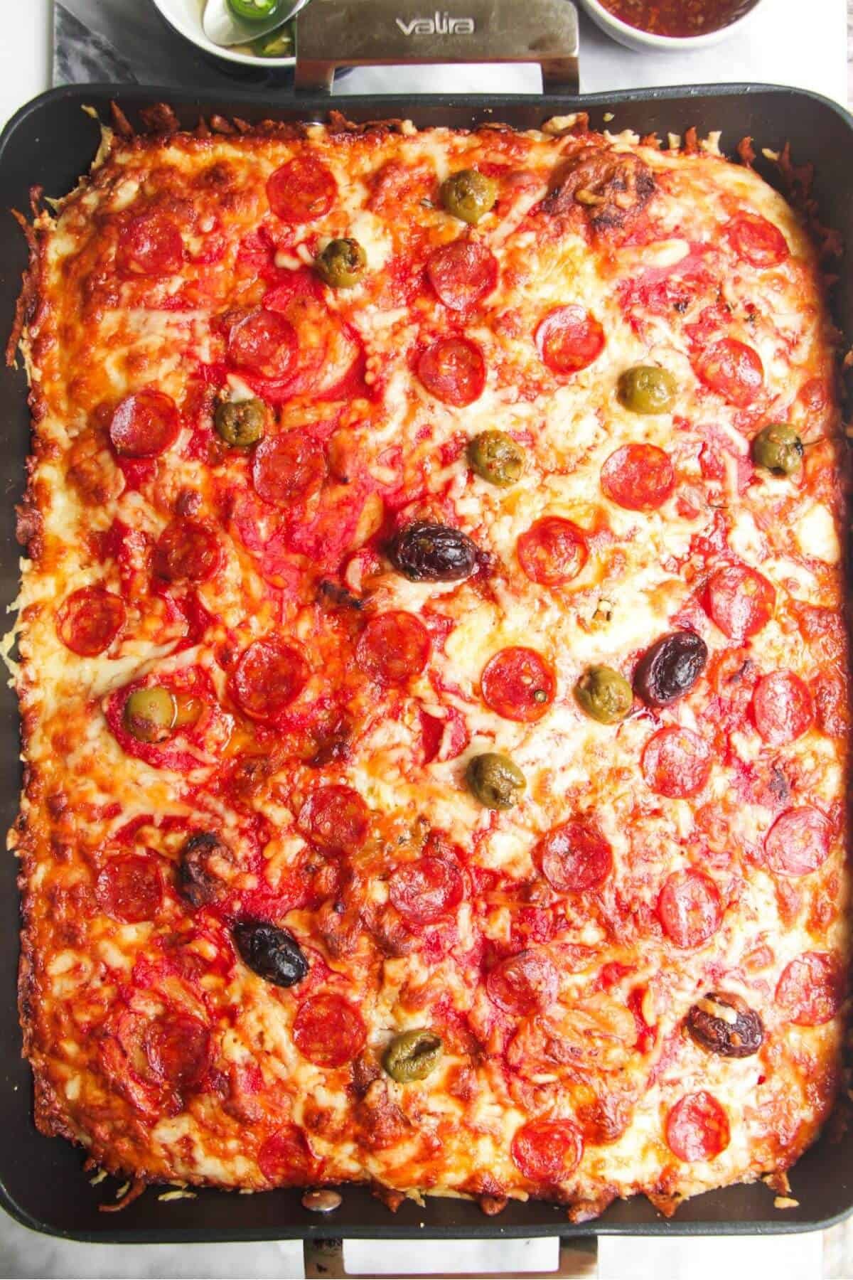 Focaccia pizza baked and golden in a large oven dish.