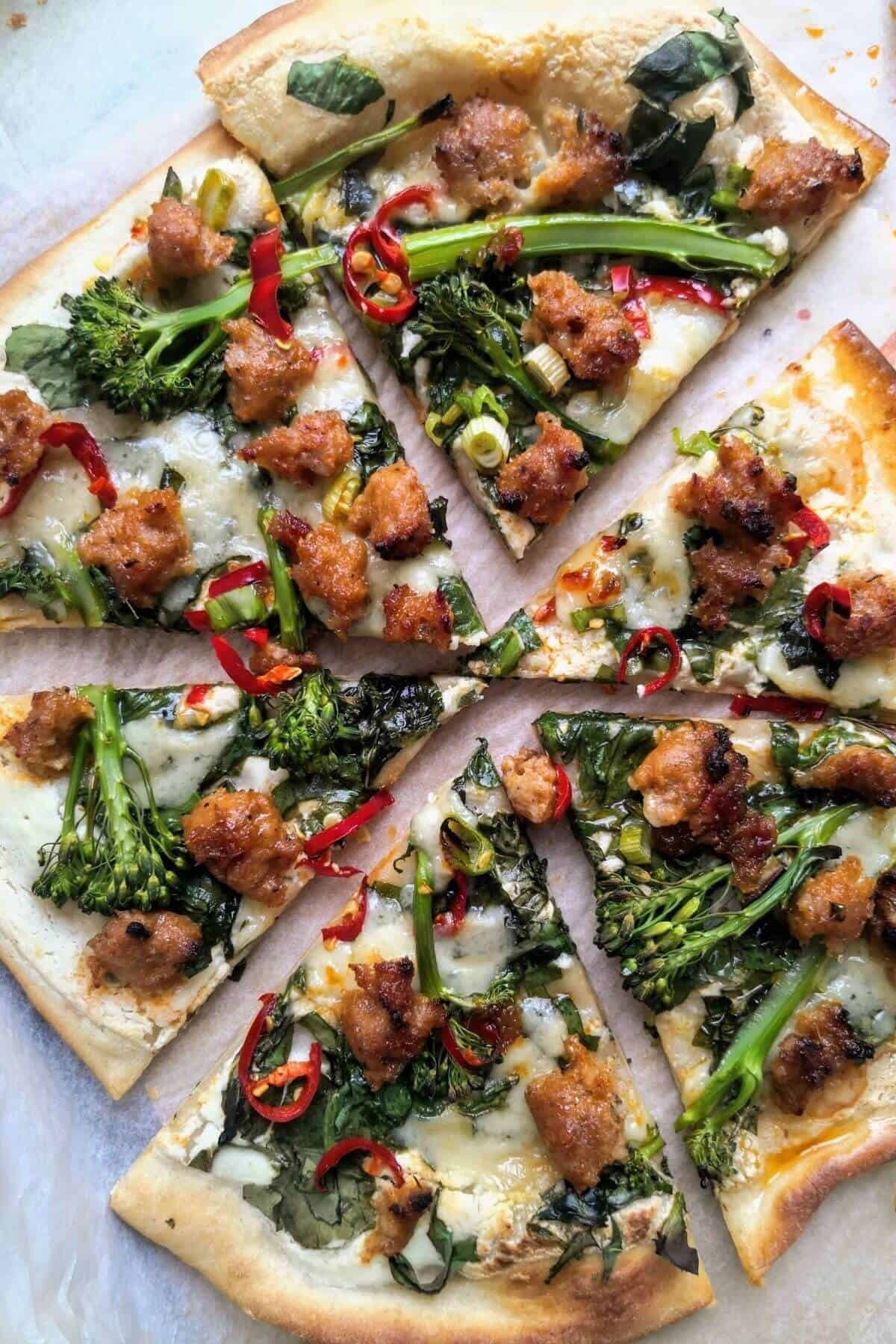 Whipped ricotta, sausage, broccolini and chilli pizza sliced.