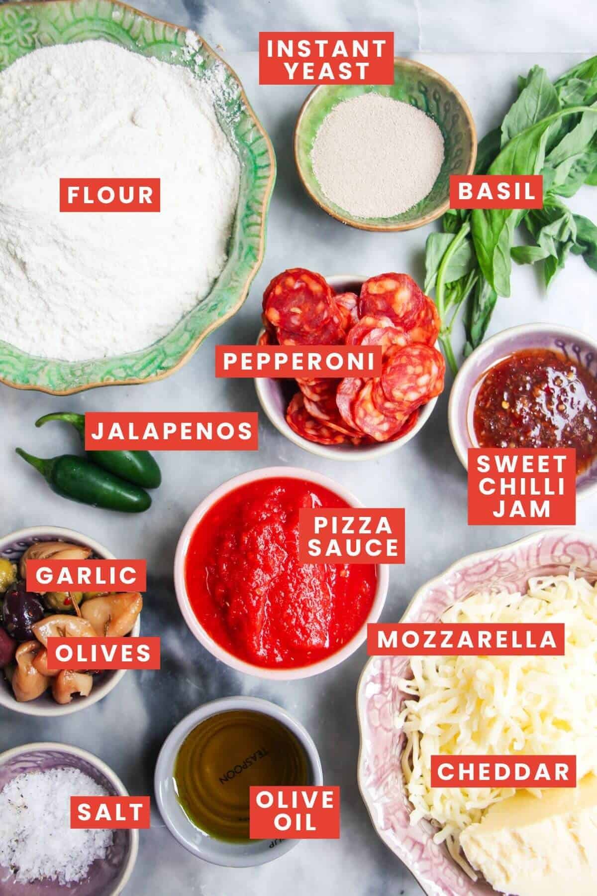 Focaccia pizza ingredients laid out on a grey marble background and labelled.
