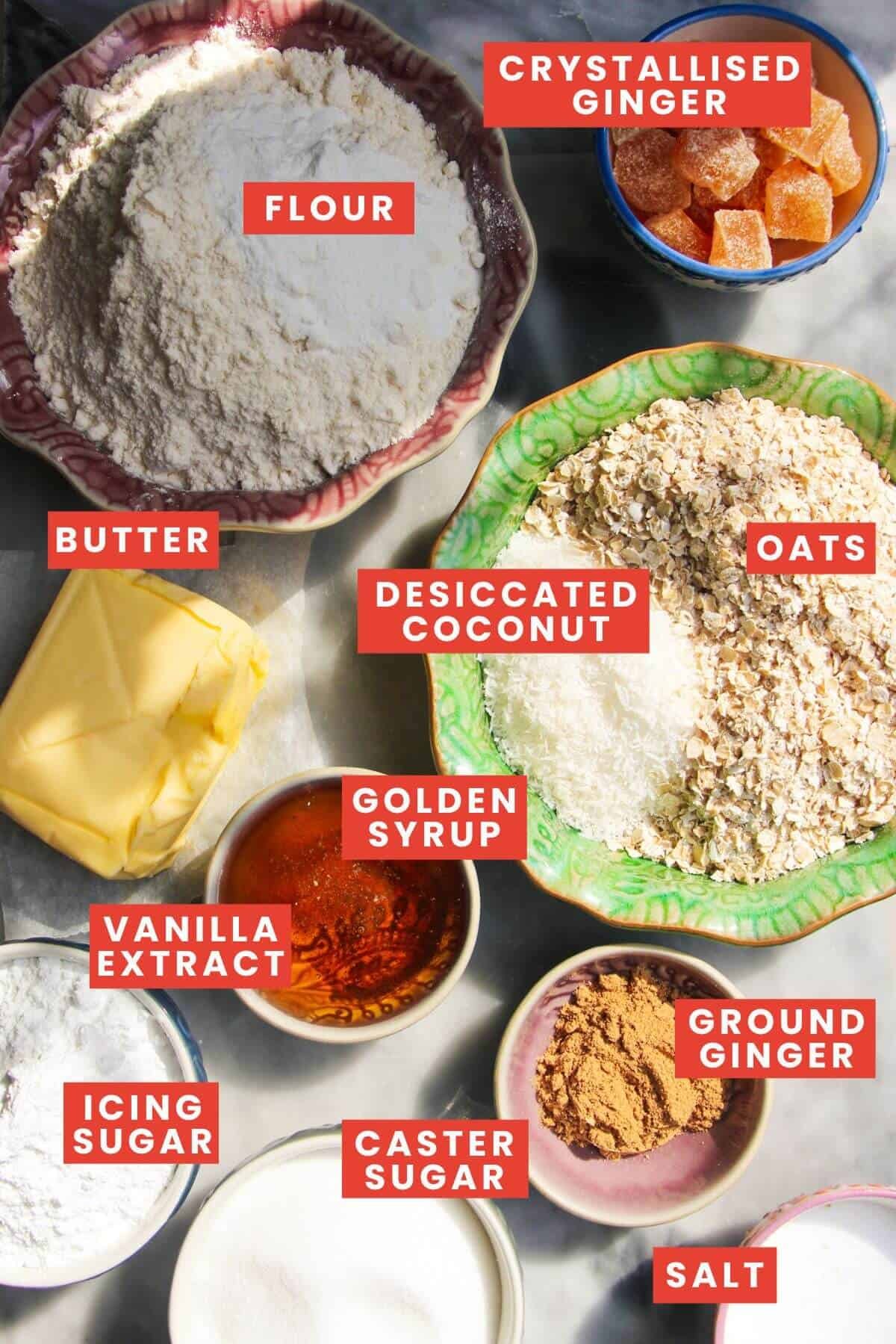 Ingredients for ginger crunch laid out on a grey marble background and labelled.