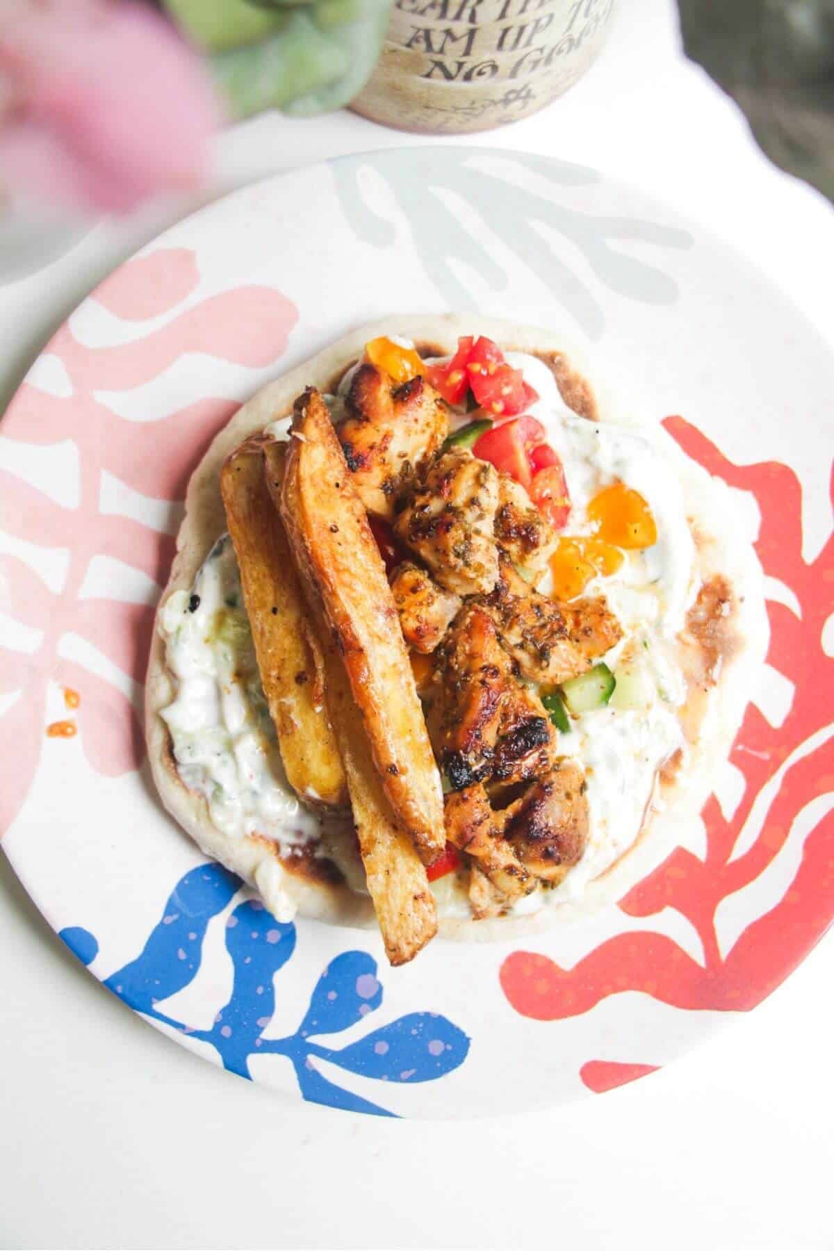 Chicken, tzatziki and fries on top of a flatbread with salad.