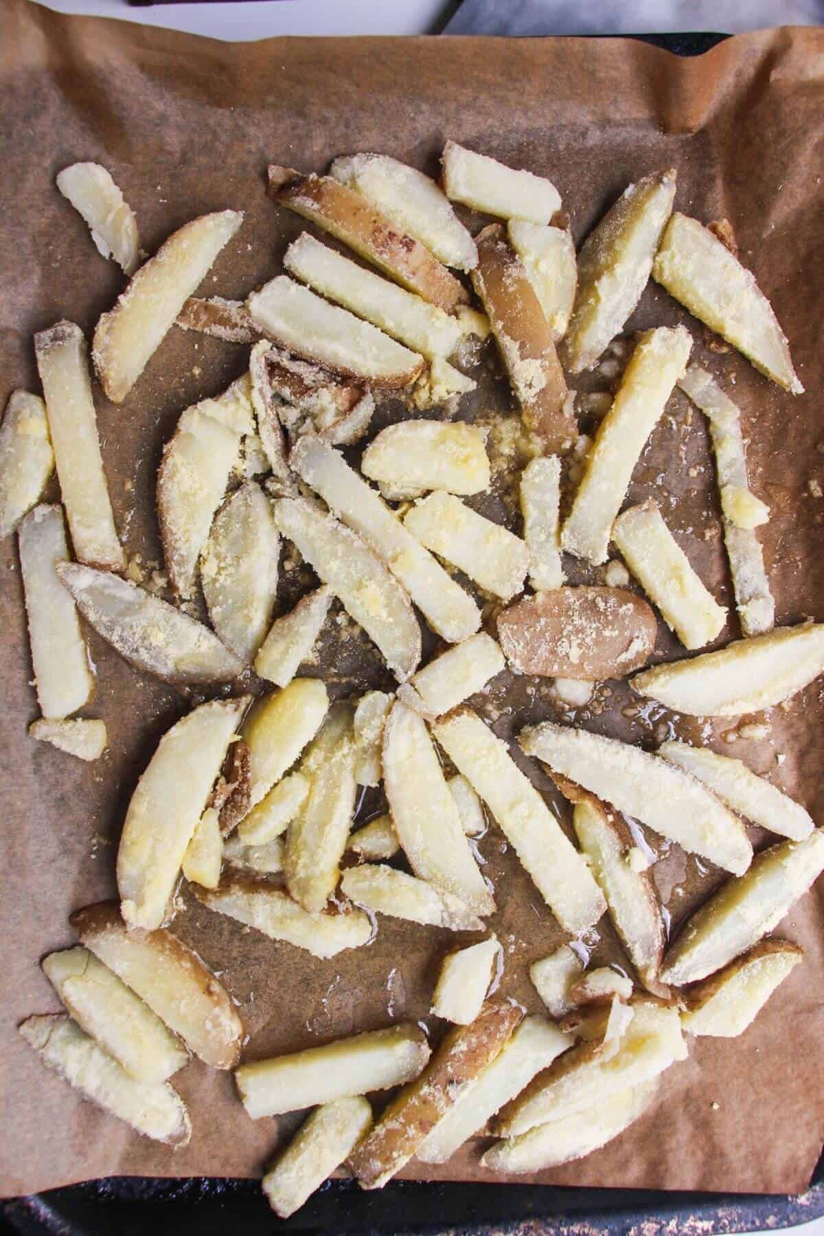 Par-boiled fries tossed with polenta, on a baking paper lined tray.