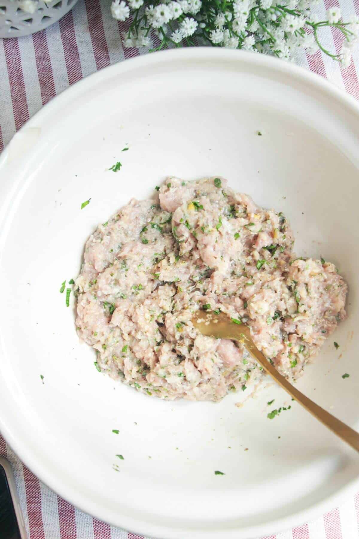 Greek chicken meatball mixture combined in a large mixing bowl.