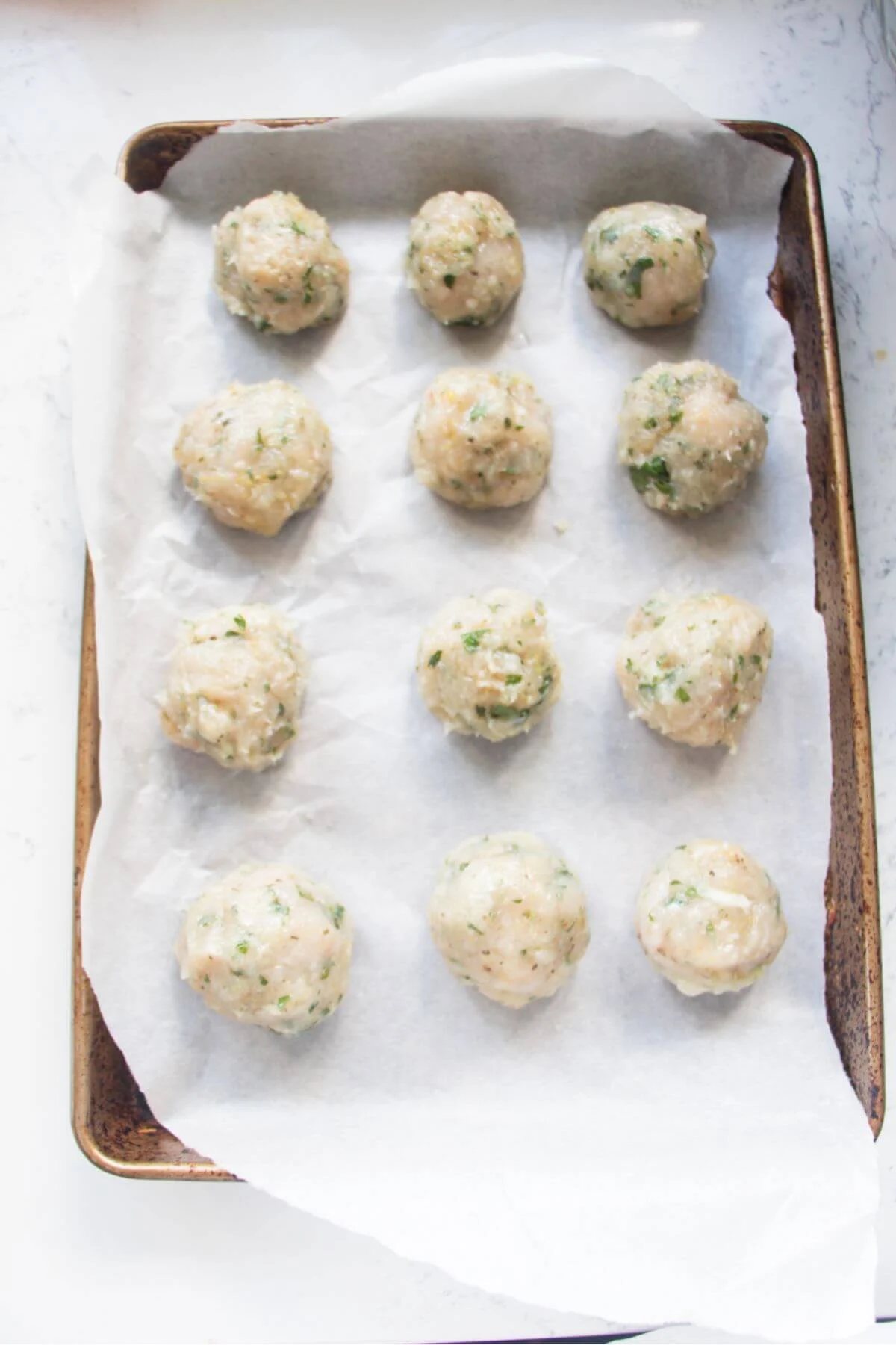 12 meatballs on a baking paper lined oven tray.