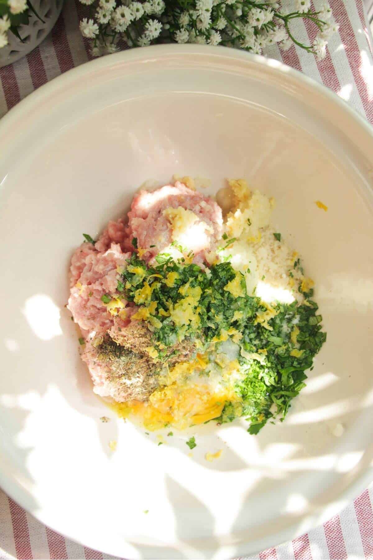 Ingredients for Greek chicken meatballs in a large mixing bowl.