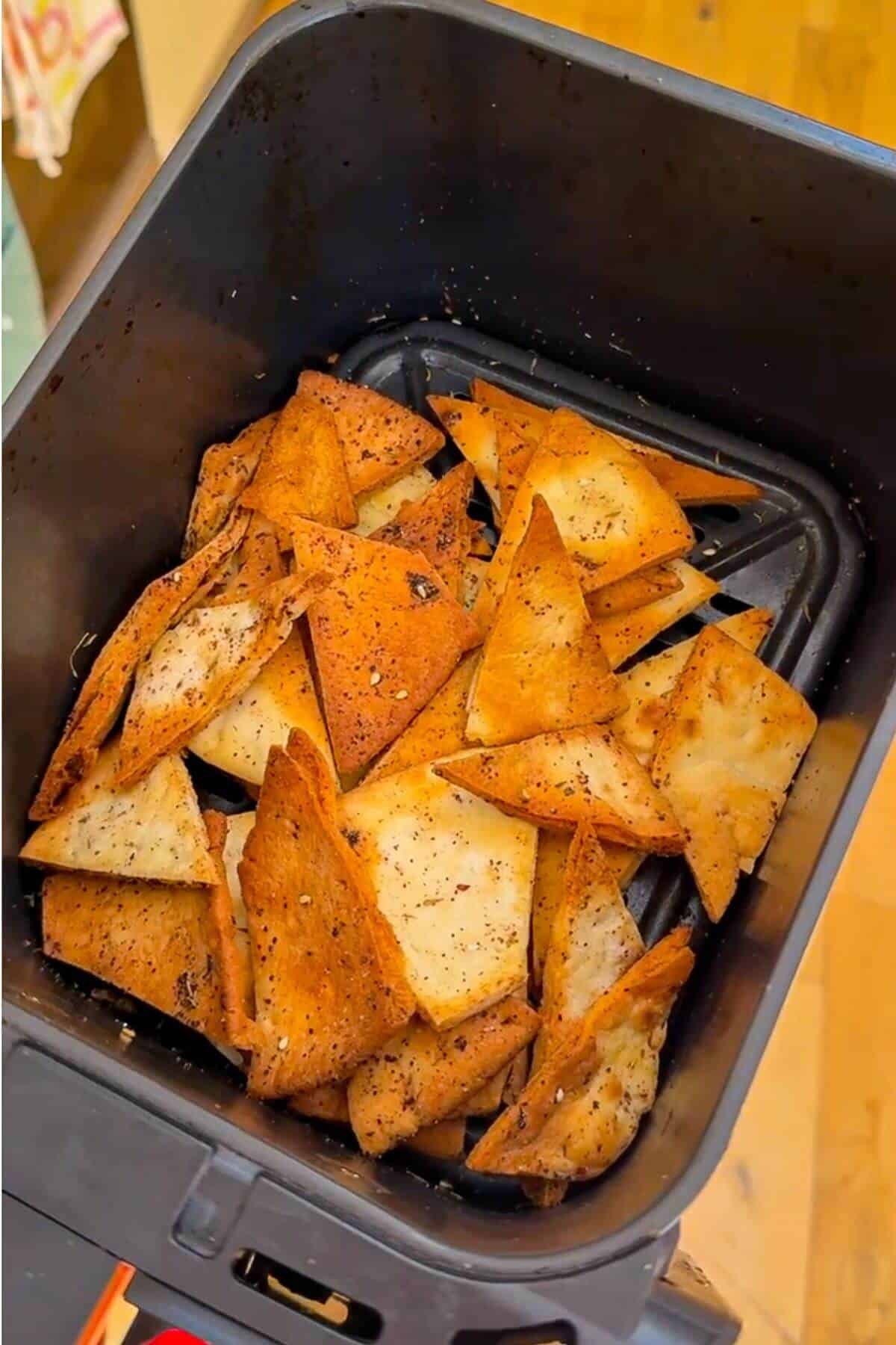 Pita chips in air fryer basket.