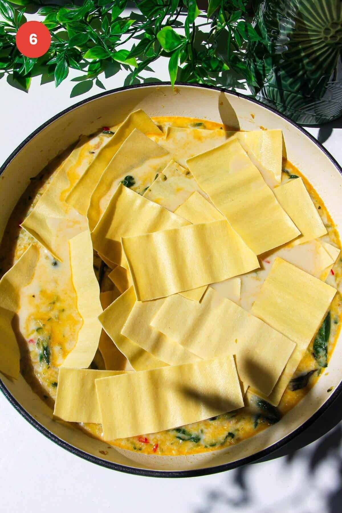 Lasagna sheets added to greens in large skillet.